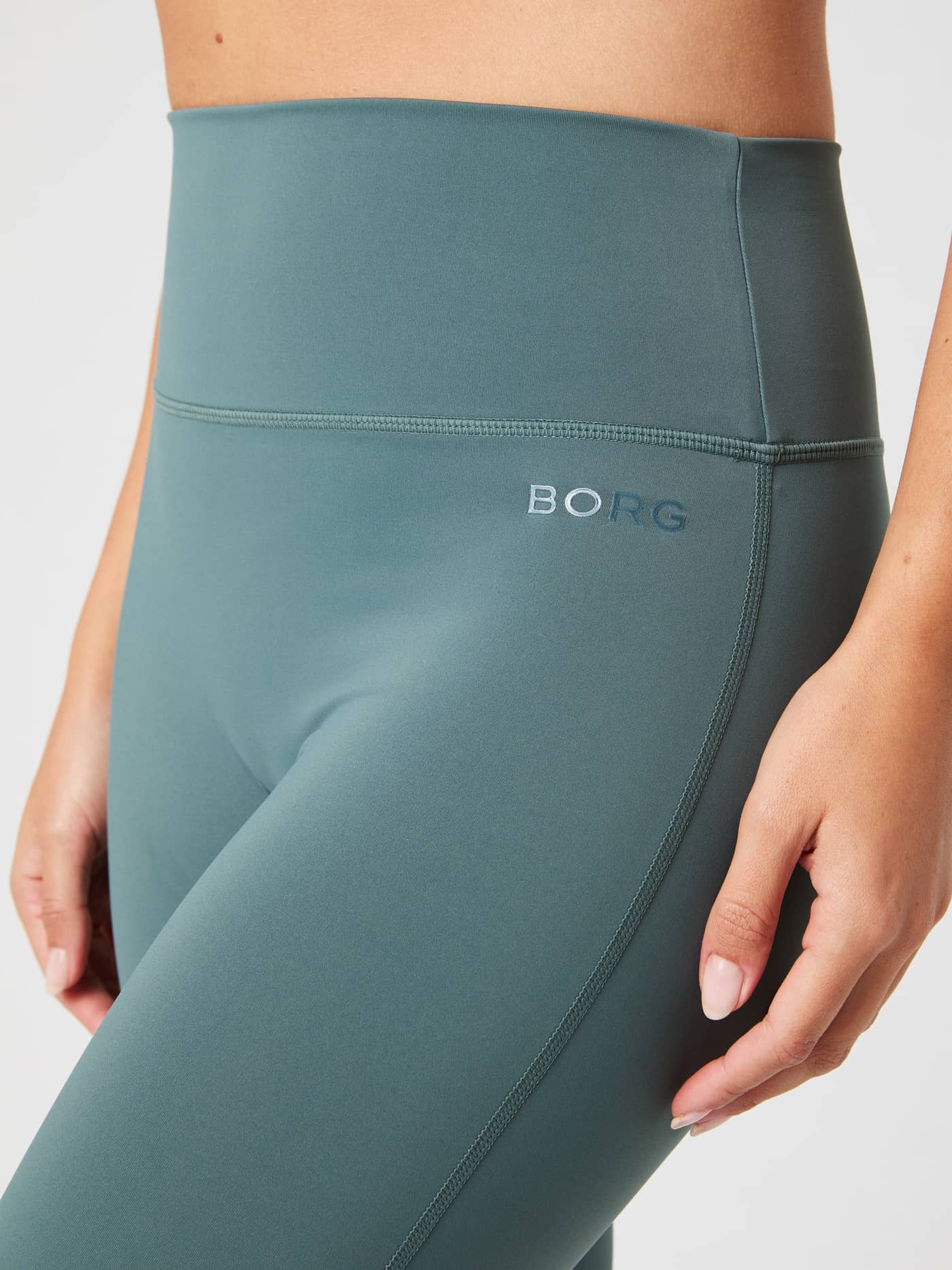 Close-up of the women's Borg Flare Tights Tall in Balsam Green (Green), featuring the high waist and tonal logo for training. - Image 4