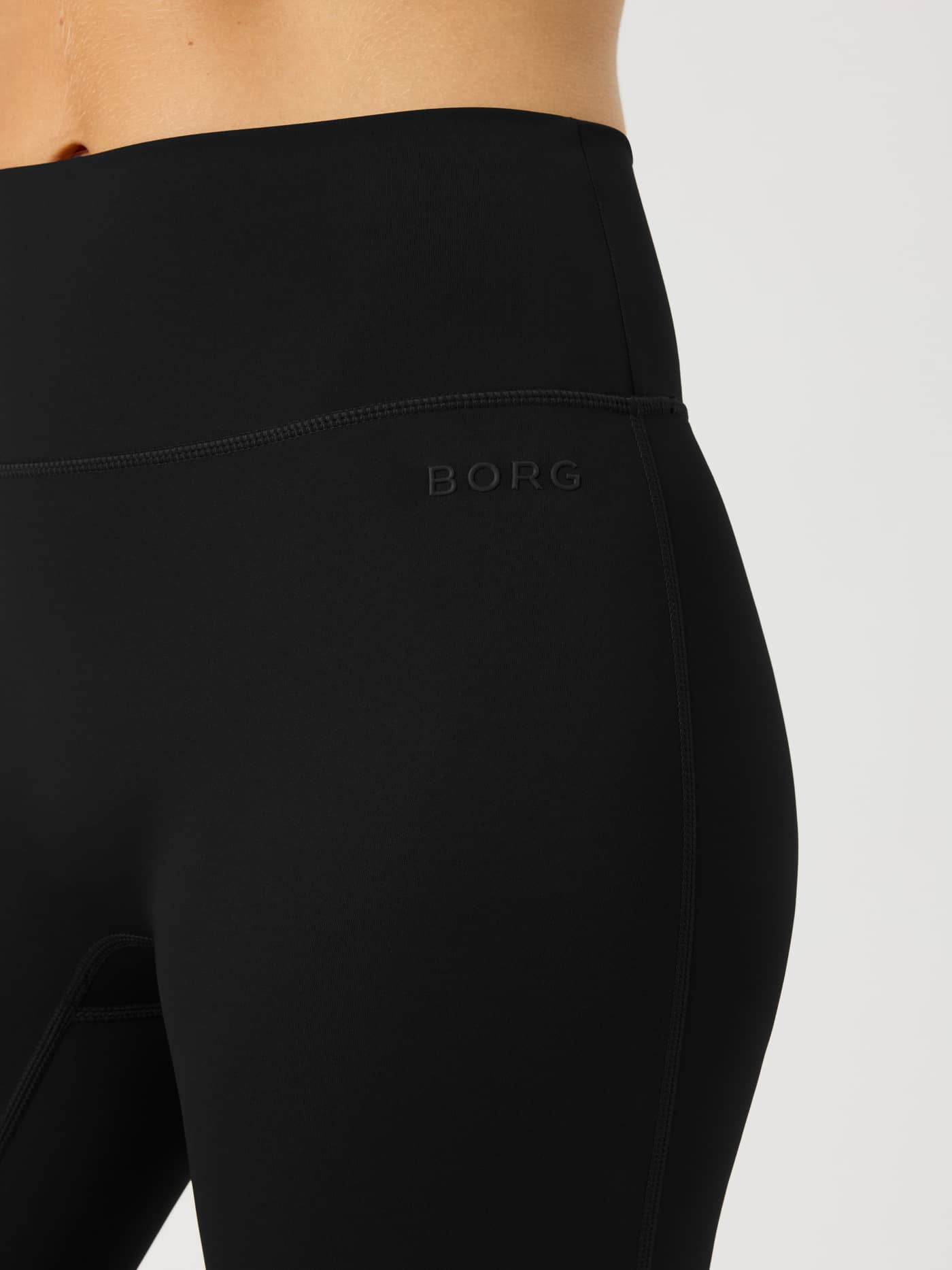 Close-up of the high-stretch Borg Flare Tights Tall in Black Beauty (Black) for training, featuring a tonal waist logo. - Image 6