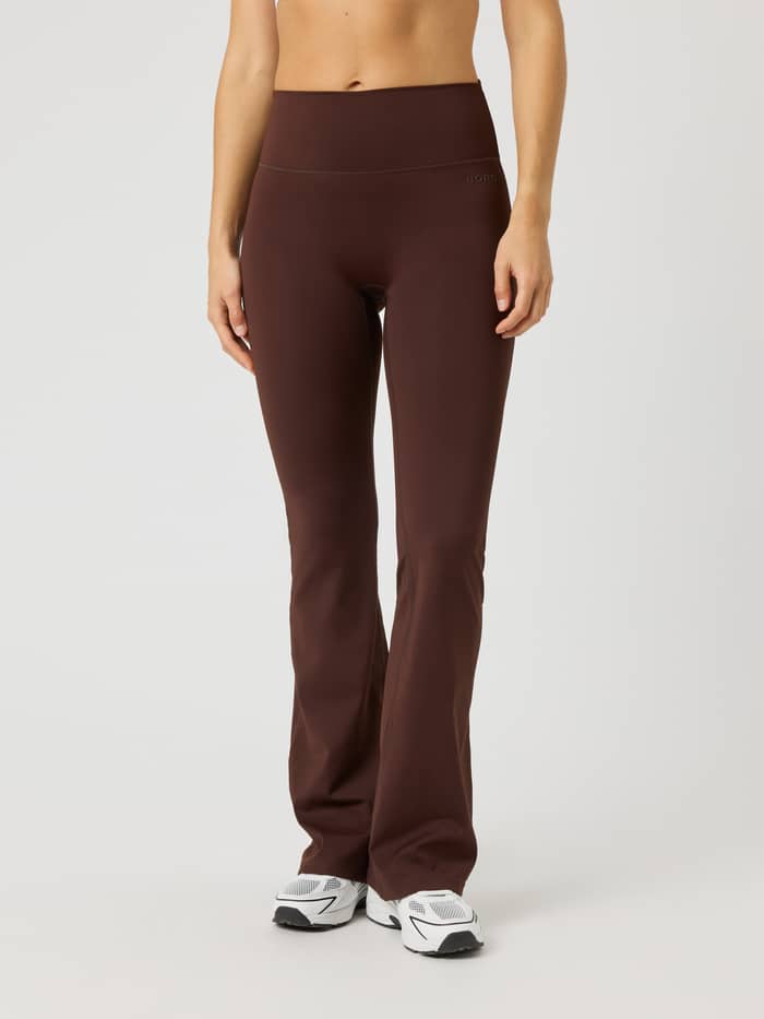 Vooraanzicht van de Borg Flare Tights Tall in Coffee Bean (Bruin) met uitlopende pijpen en tonaal logo voor training.