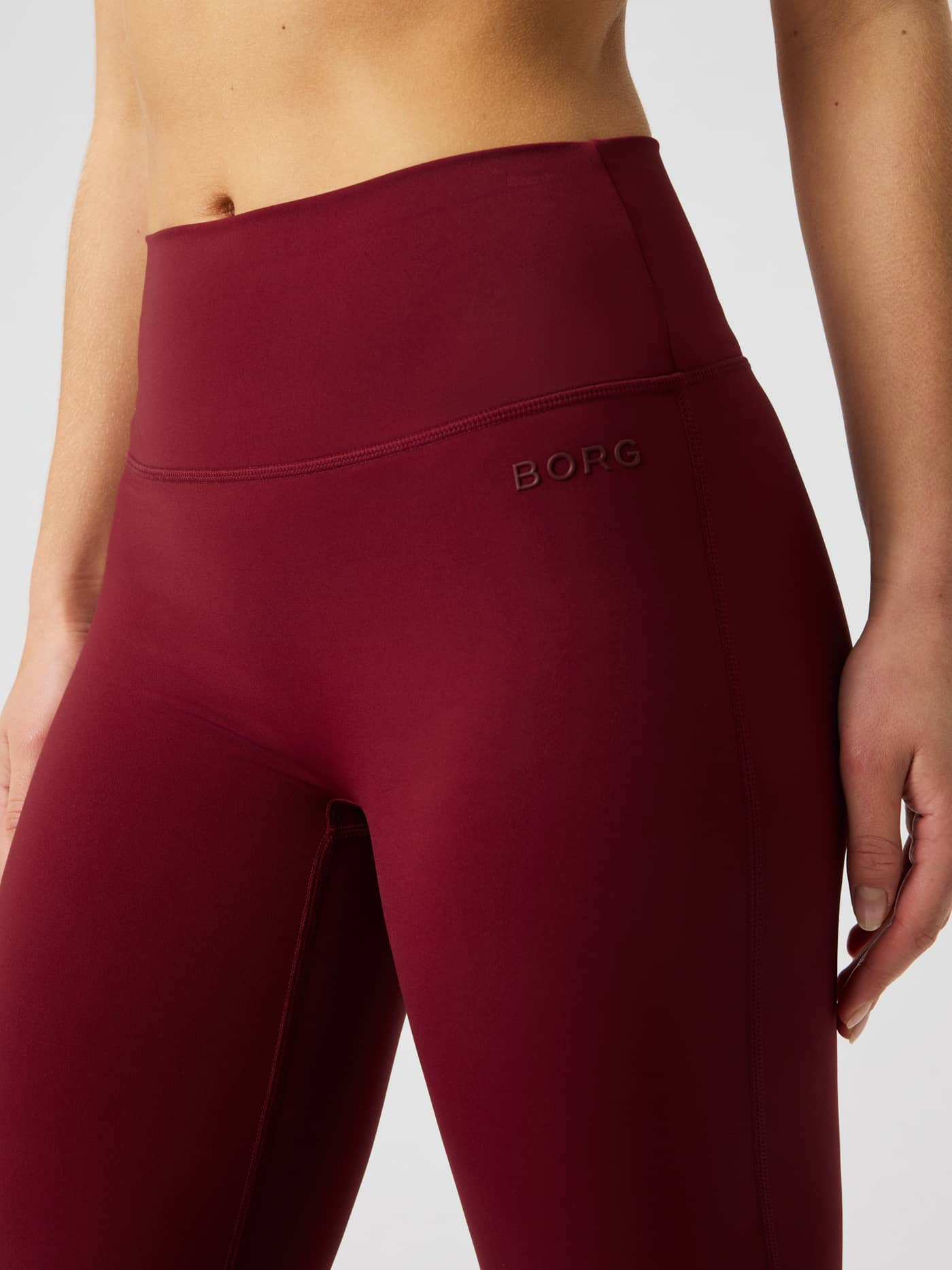 Nærbilde av den høye linningen på BORG FLARE TIGHTS TALL i Cabernet (rød), med en diskré ton-i-ton-logo. - Image 4