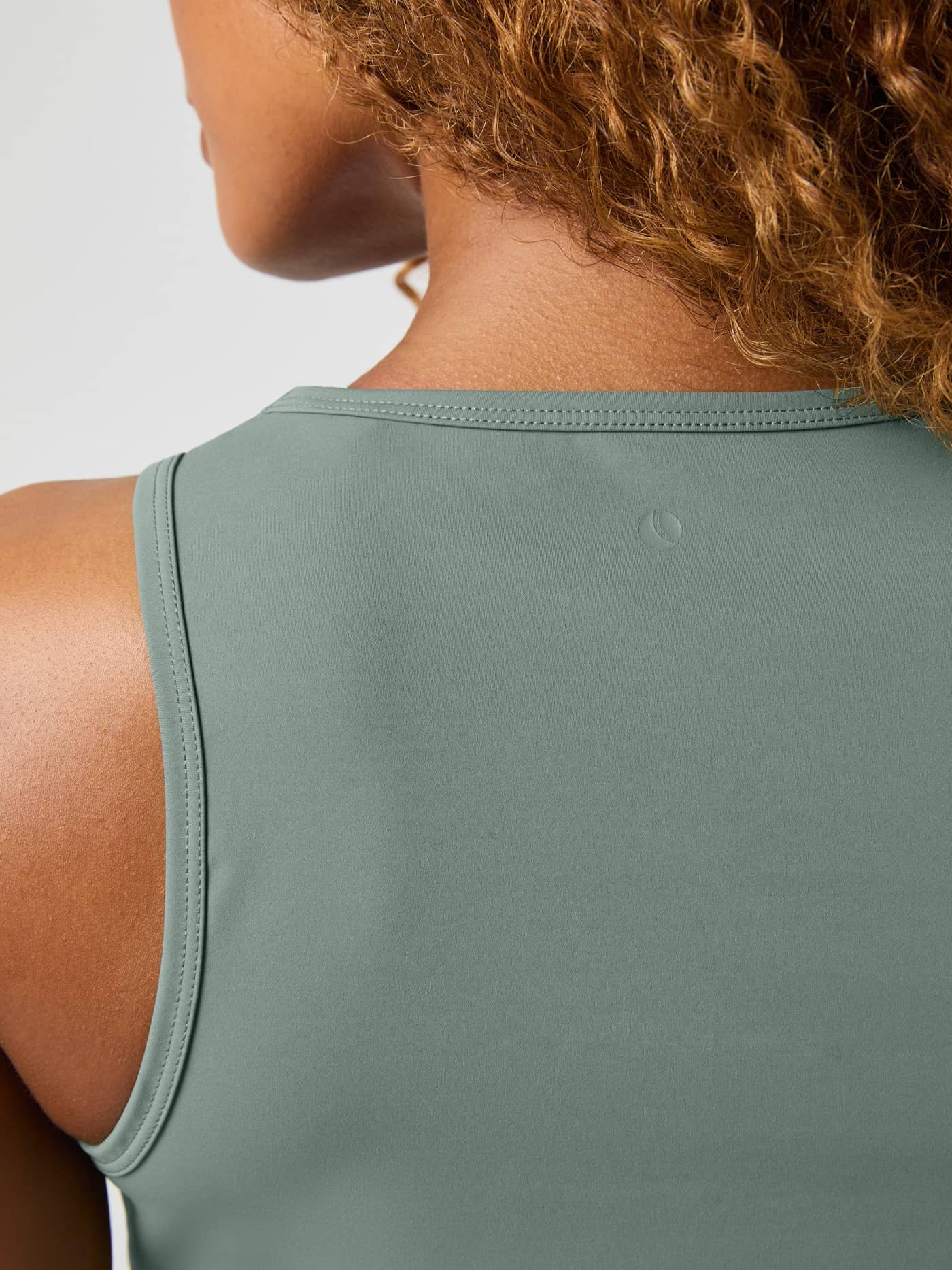 Close-up back view of the training Studio Cross Tank Top in Agave Green (Green) featuring a subtle tonal logo. - Image 5