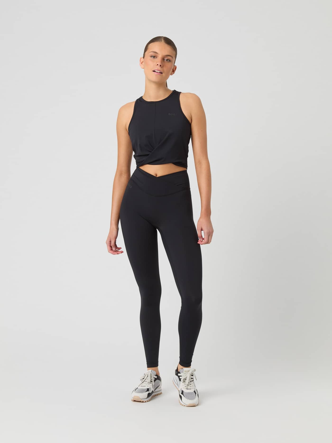 Studio Cross Tank Top i Black Beauty (Sort) set forfra med en snoet designdetalje ideel til træning. - Image 3