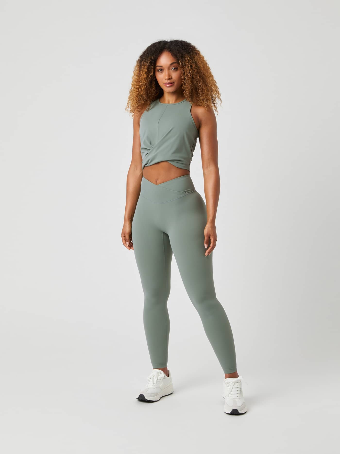 Full-body front view of a woman wearing the Agave Green (Green) Studio Cross Tank Top in a high-stretch training fit. - Image 3