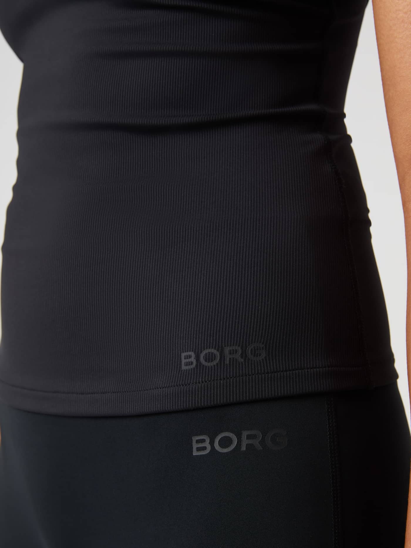 Närbild på Studio Ribbed Strap Tank Top i Black Beauty (Svart) med ribbad struktur och svart Borg-logotyp för träning. - Image 6