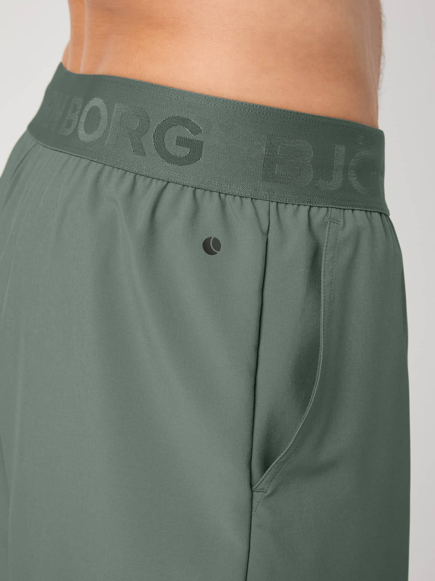 Close-up of the Agave Green (Green) Borg 2 In 1 Shorts for training, featuring a branded waistband and black logo. - Image 6