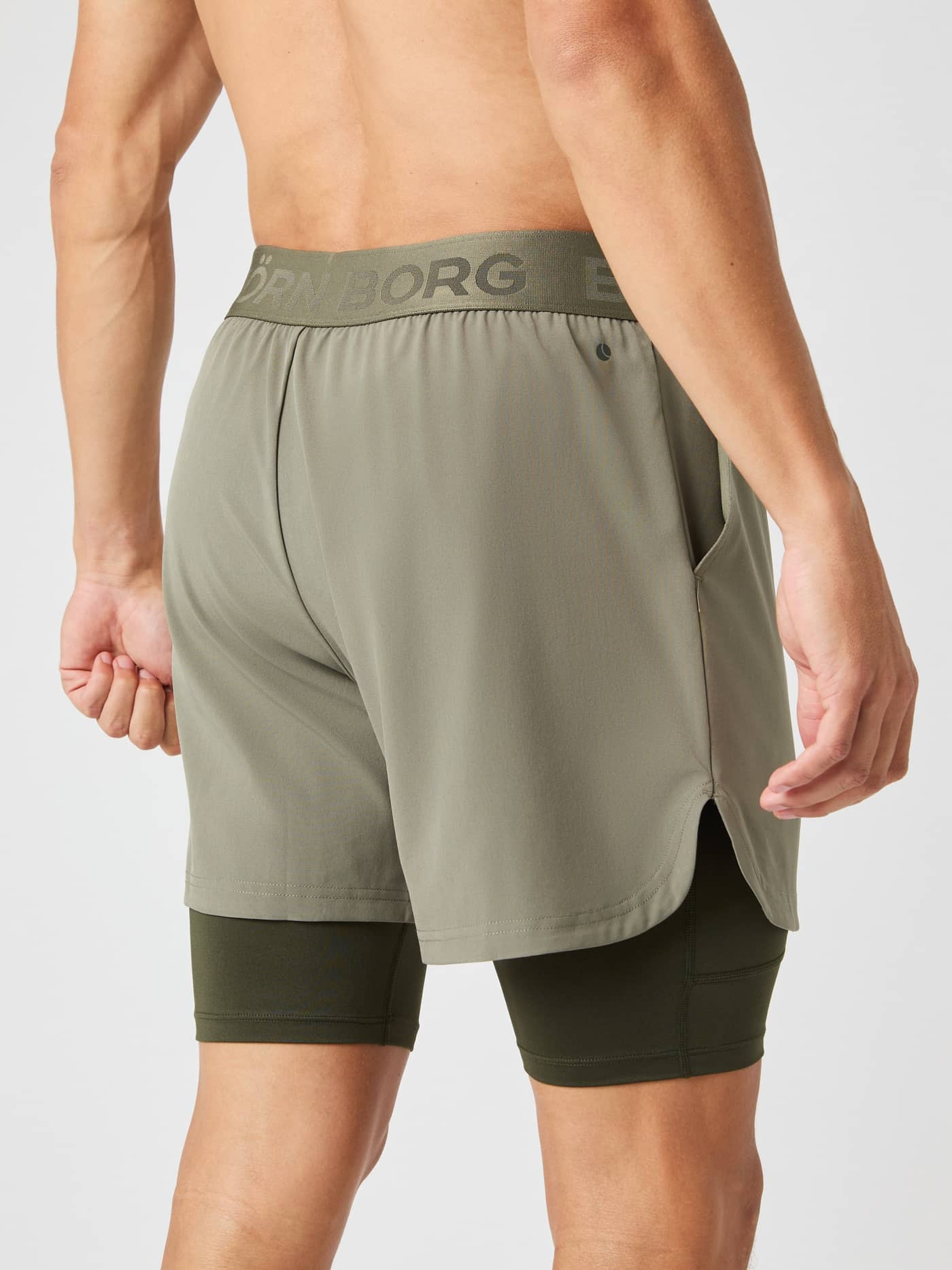 Vista posterior de un hombre con los Borg 2 In 1 Shorts en Dusty Olive (Verde) y cintura con logo para entrenamiento. - Image 2