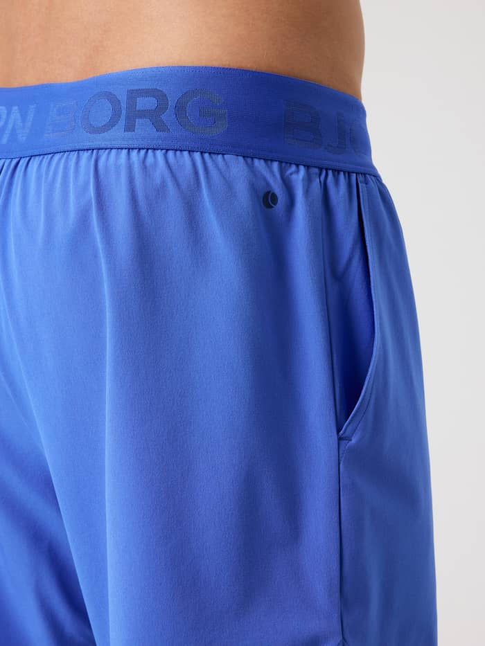 Zijaanzicht van de Borg 2 In 1 Shorts in Amparo Blue (Blauw) voor training met een merk-tailleband en tennislogo. - Image 3