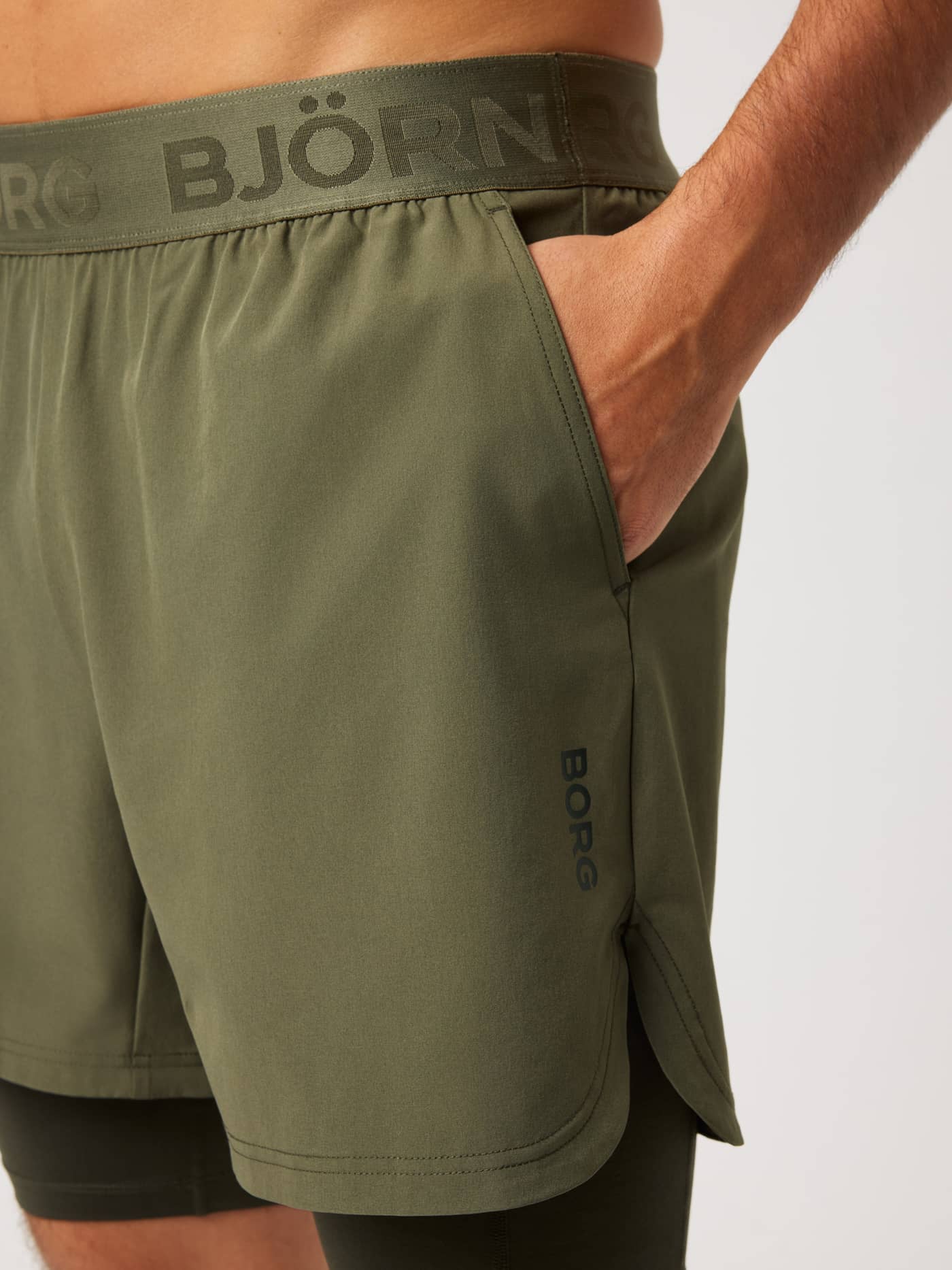Close-up of the Borg 2 In 1 Shorts in Kalamata (Green) with a black logo and side slit for training mobility. - Image 4