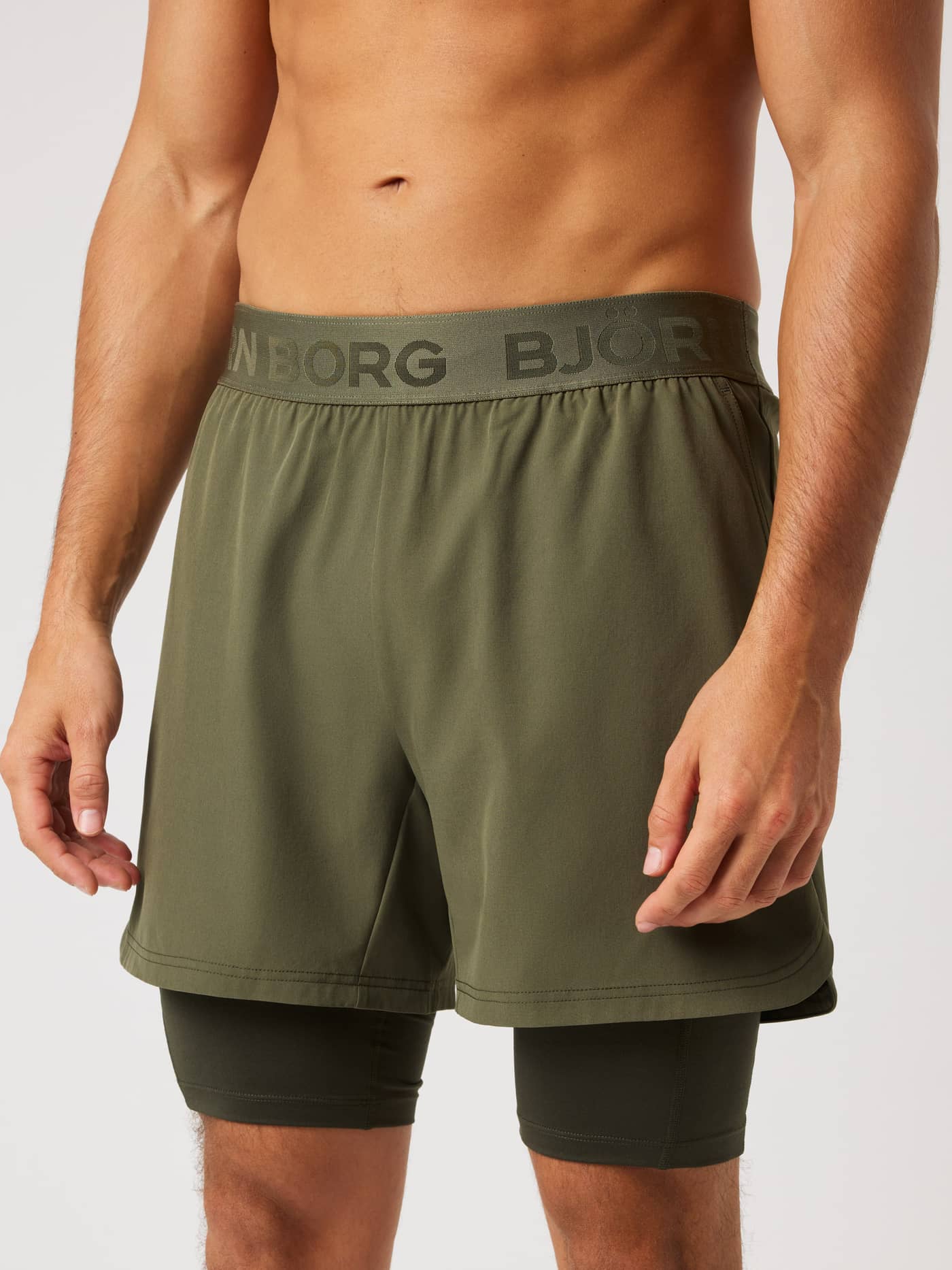 Front view of a model in Borg 2 In 1 Shorts in Kalamata (Green) with a supportive inner layer for training and tennis. - Image 1