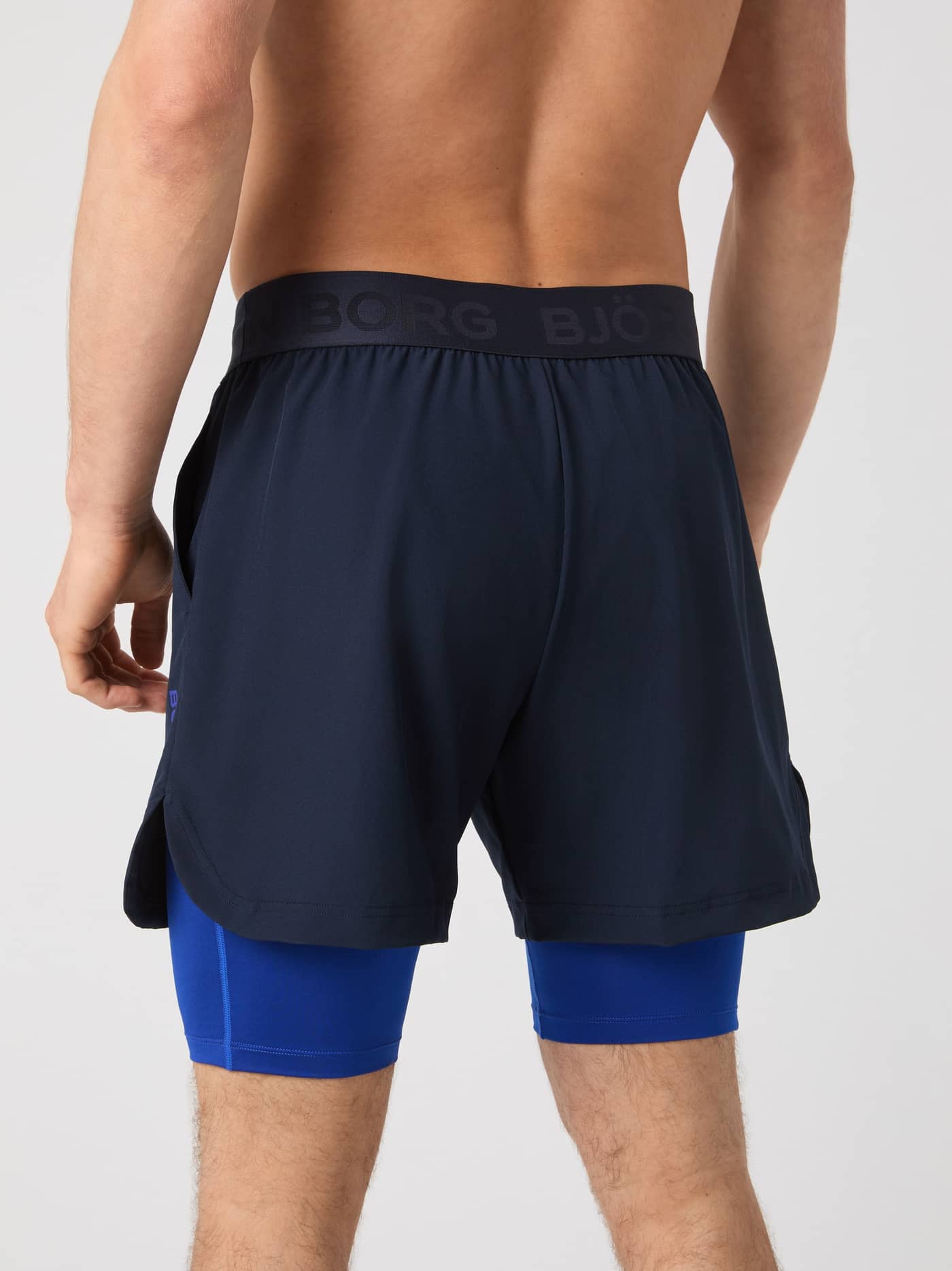Achteraanzicht van een man in de Borg 2 In 1 Shorts in Night sky (Marineblauw) met blauw logo voor training. - Image 2