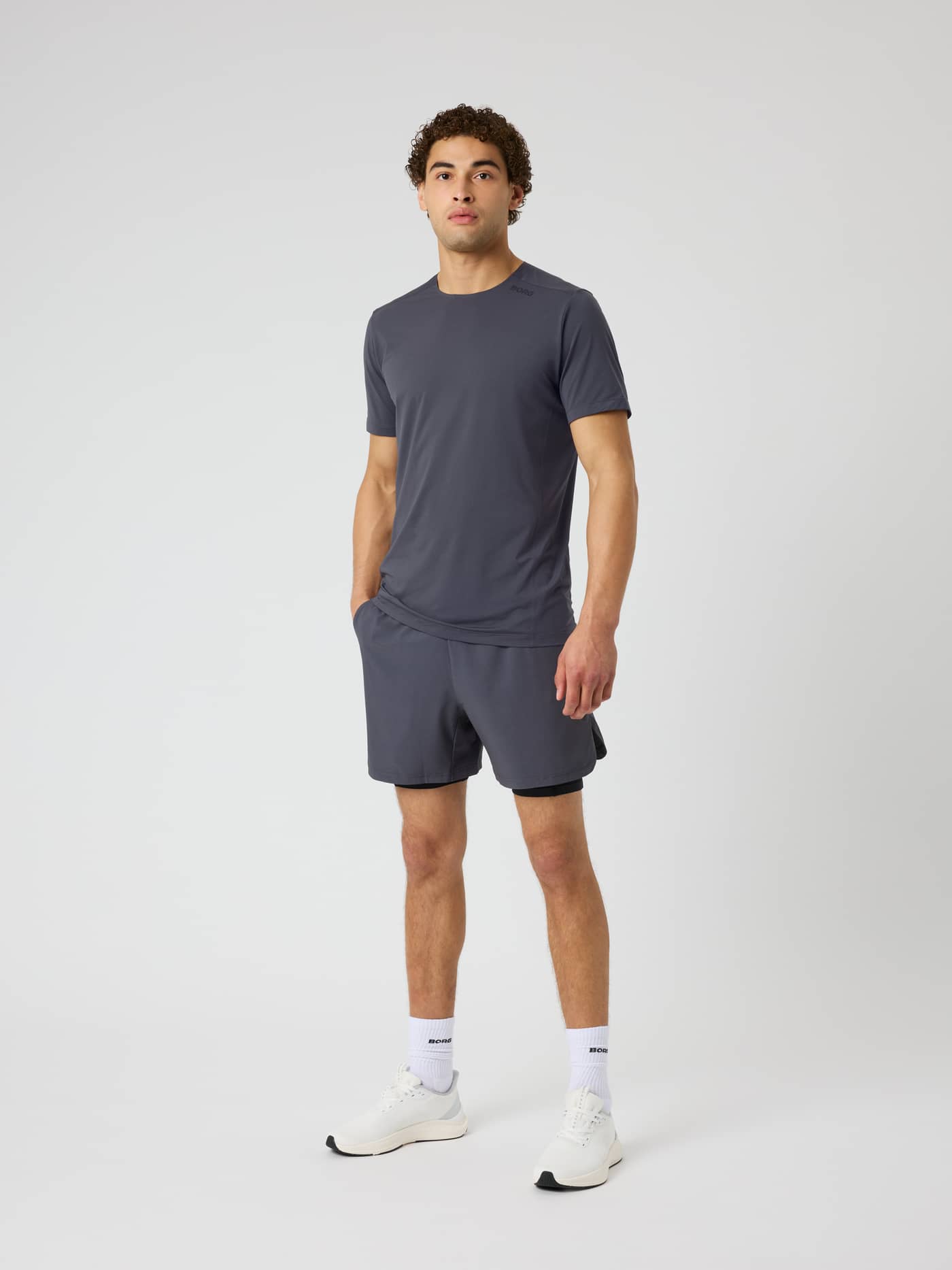 Full-body front view of a model wearing Borg 2 In 1 Shorts in Asphalt (Grey) with a black logo for gym training and running. - Image 3