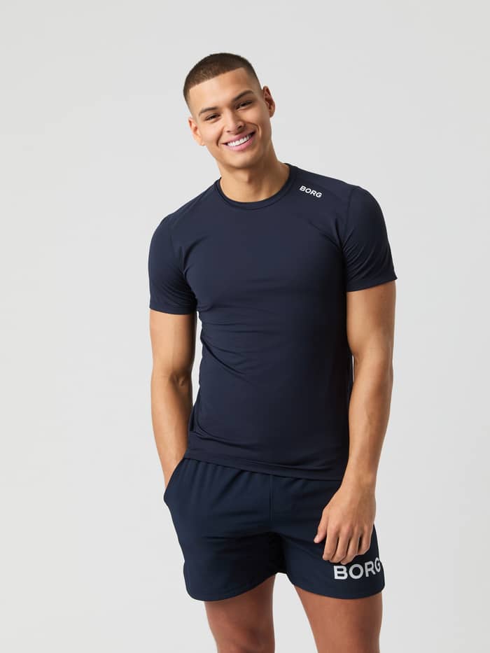 Vooraanzicht van een man in het Björn Borg Athletic T-Shirt in Night Sky (Marineblauw) met wit logo en shorts voor training.