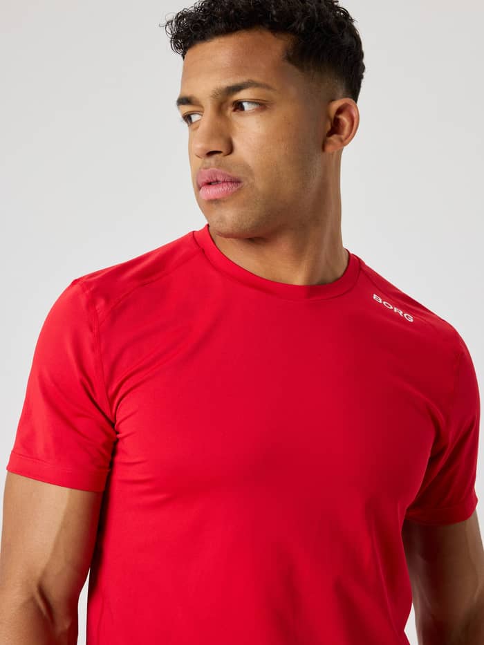Vooraanzicht van een man in het ademende Borg Athletic T-Shirt in Lychee (Rood) met wit logo voor training. - Image 4