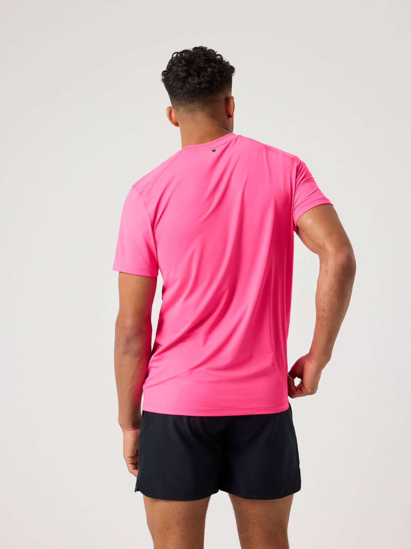 Borg Athletic T-Shirt i Pink Glo (Pink) set bagfra på en mand, en højtydende træningstop med et lille sort logo. - Image 2
