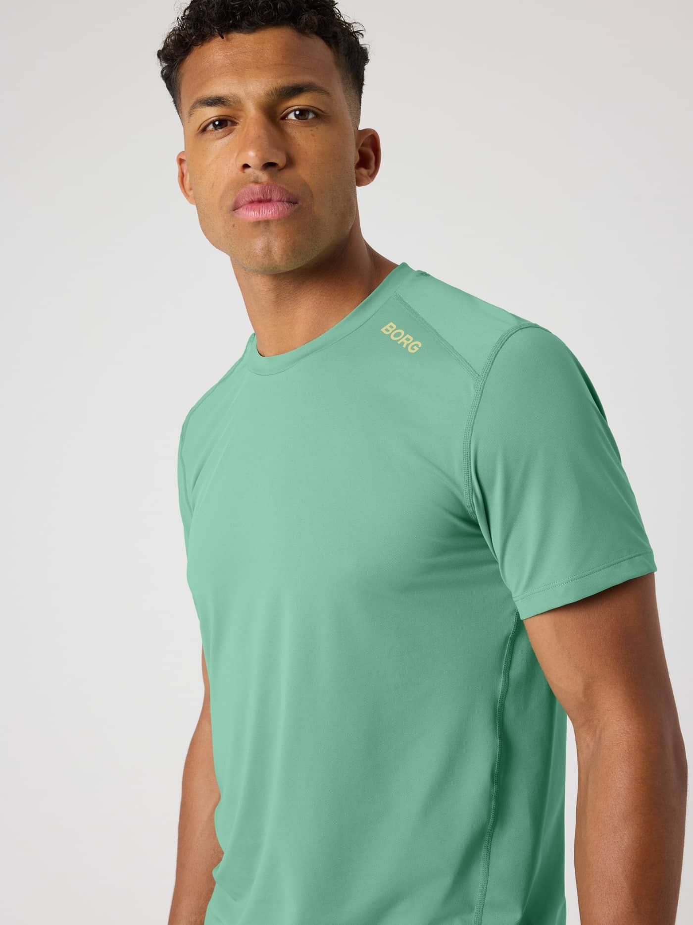 Front view of a man wearing the Malachite Green (Green) Borg Athletic T-Shirt for training with a gold shoulder logo. - Image 5