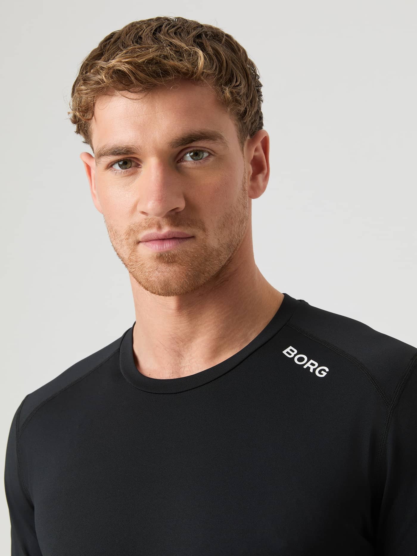Close-up of a model wearing the black Borg Athletic T-shirt, showing the shoulder logo and fabric detail. - Image 4