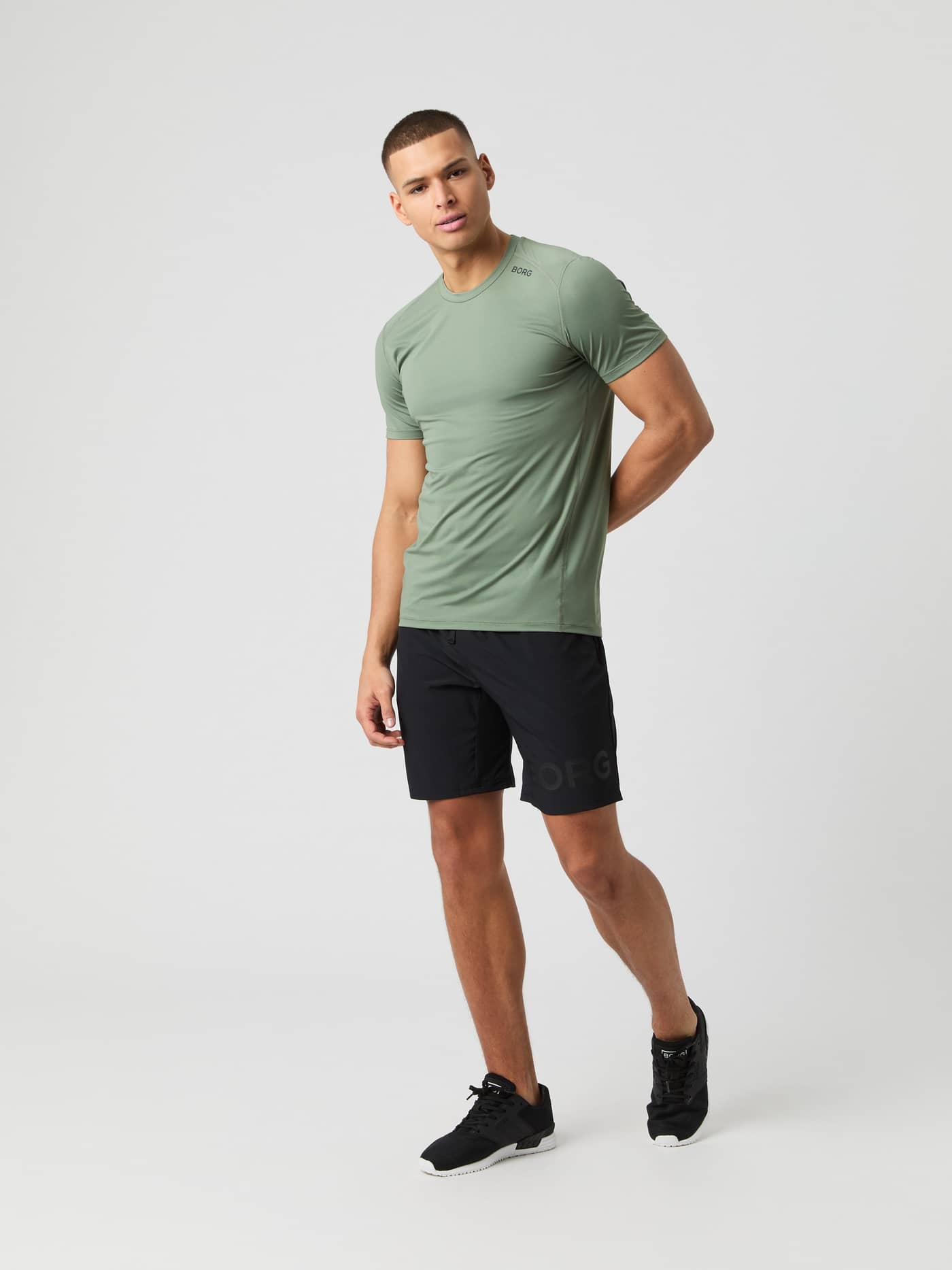 Male model wears the Björn Borg Athletic T-shirt in Agave Green with black shorts, full body shot. - Image 3