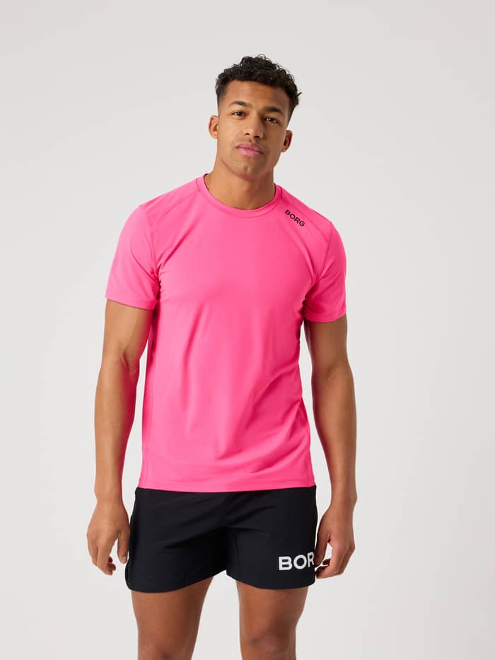Modell framifrån i Borg Athletic T-Shirt i Pink Glo (Rosa) för träning med en svart logotyp på axeln.