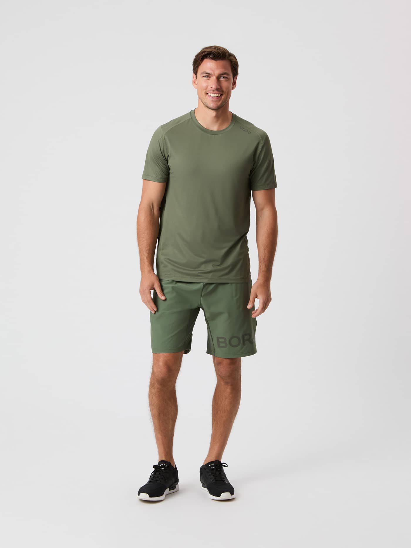 Modell framifrån i Borg Athletic T-Shirt i Thyme (Grön) med matchande shorts och svarta sneakers för funktionell träning. - Image 3