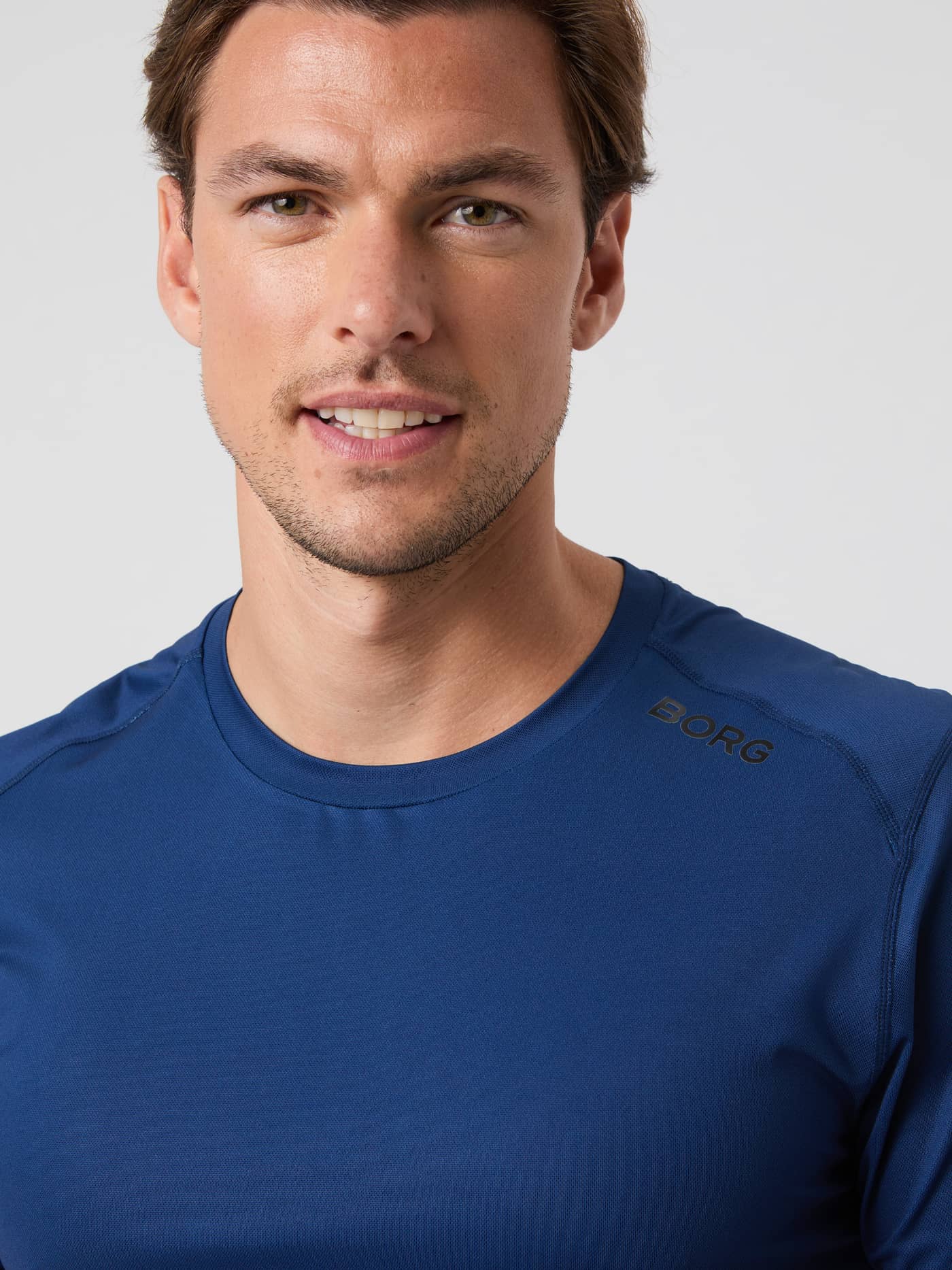 Close-up of a model wearing the Borg Athletic T-Shirt in Estate Blue, showing the neckline and logo. - Image 4