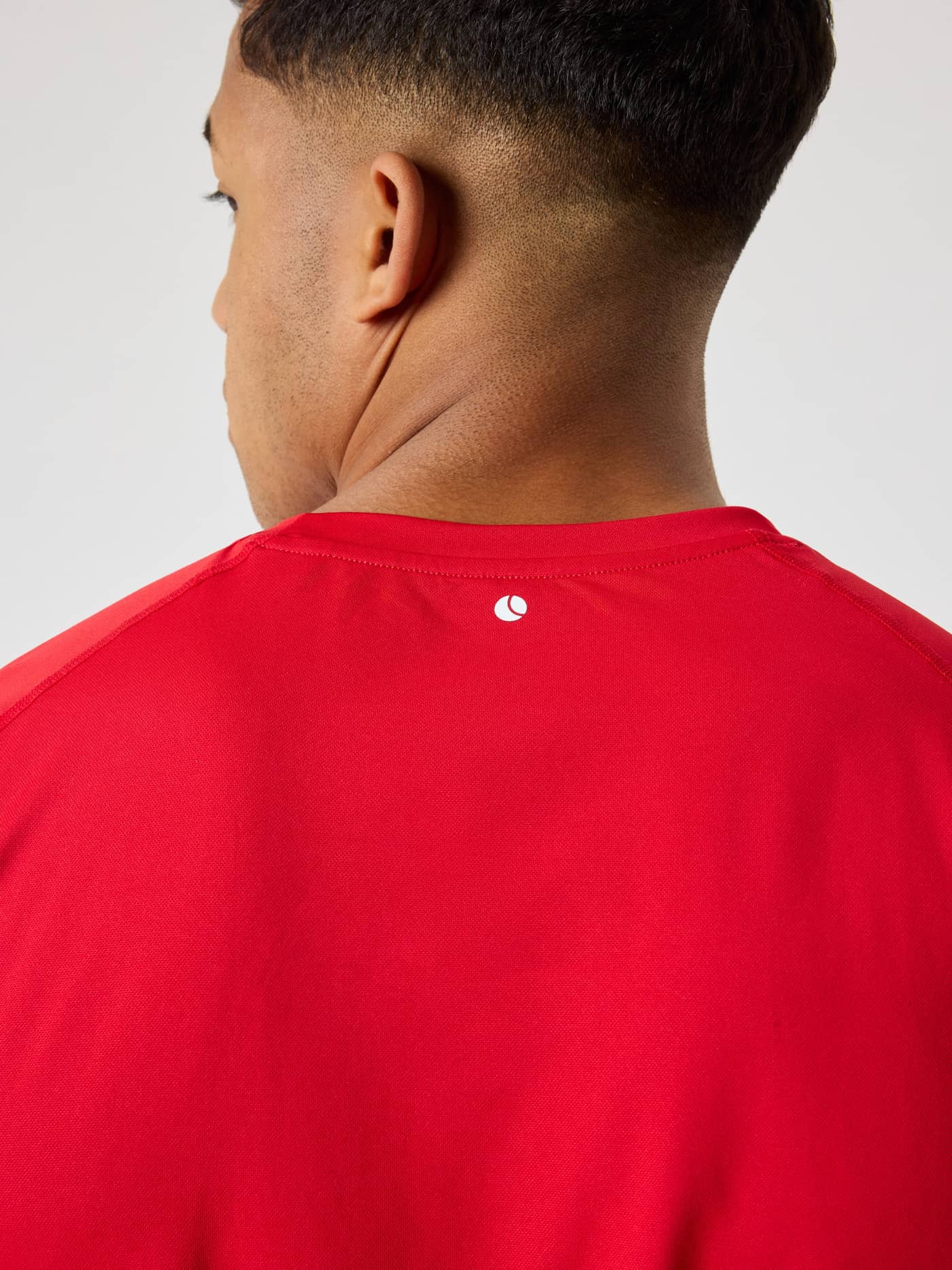 Back view of the Borg Athletic T-Shirt in Lychee (Red) featuring a white tennis logo on breathable training fabric. - Image 5