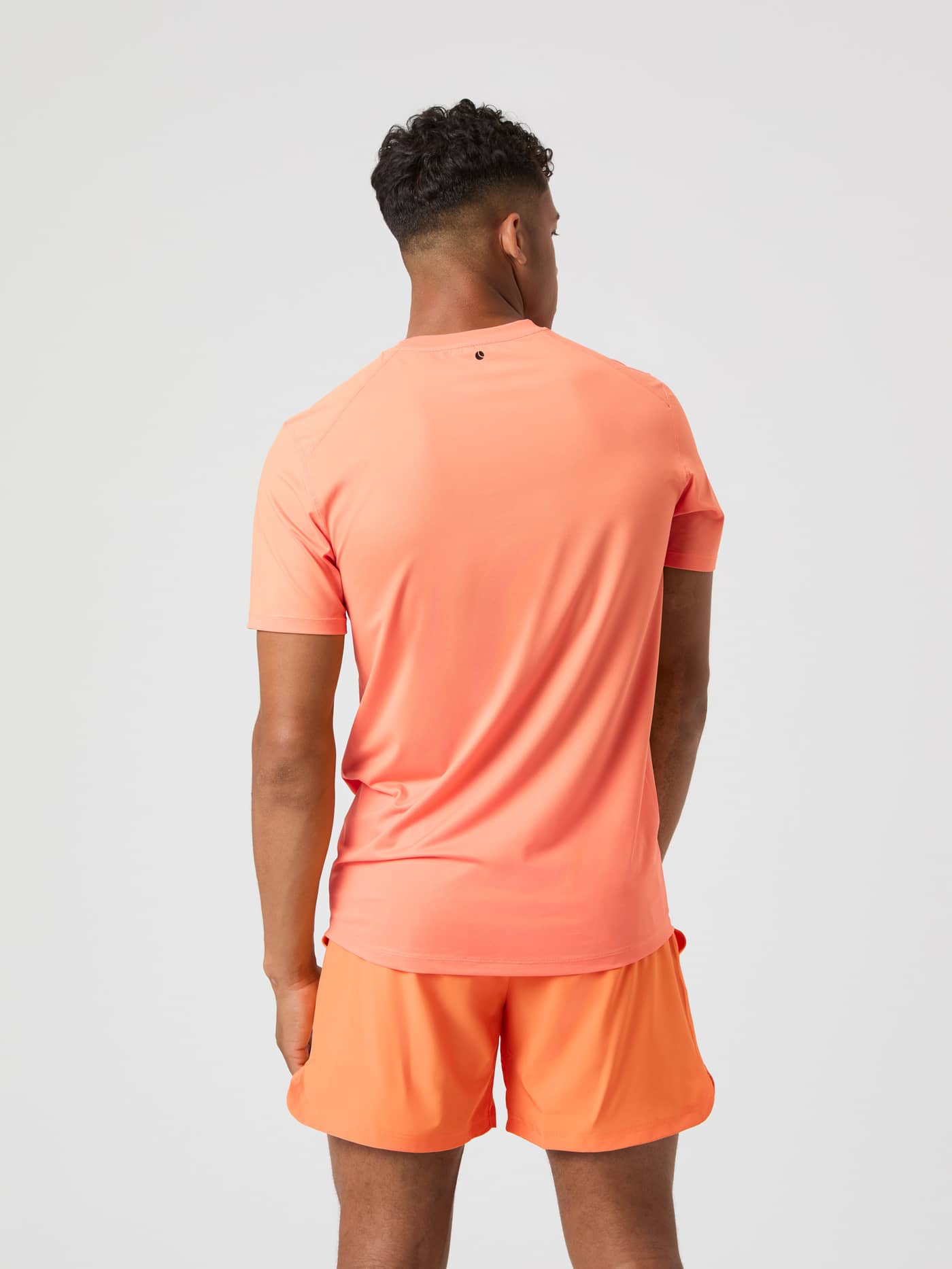 Modell sedd bakifrån i Borg Athletic T-Shirt i Papaya (Orange), en funktionell tränings-T-shirt för herrar. - Image 2