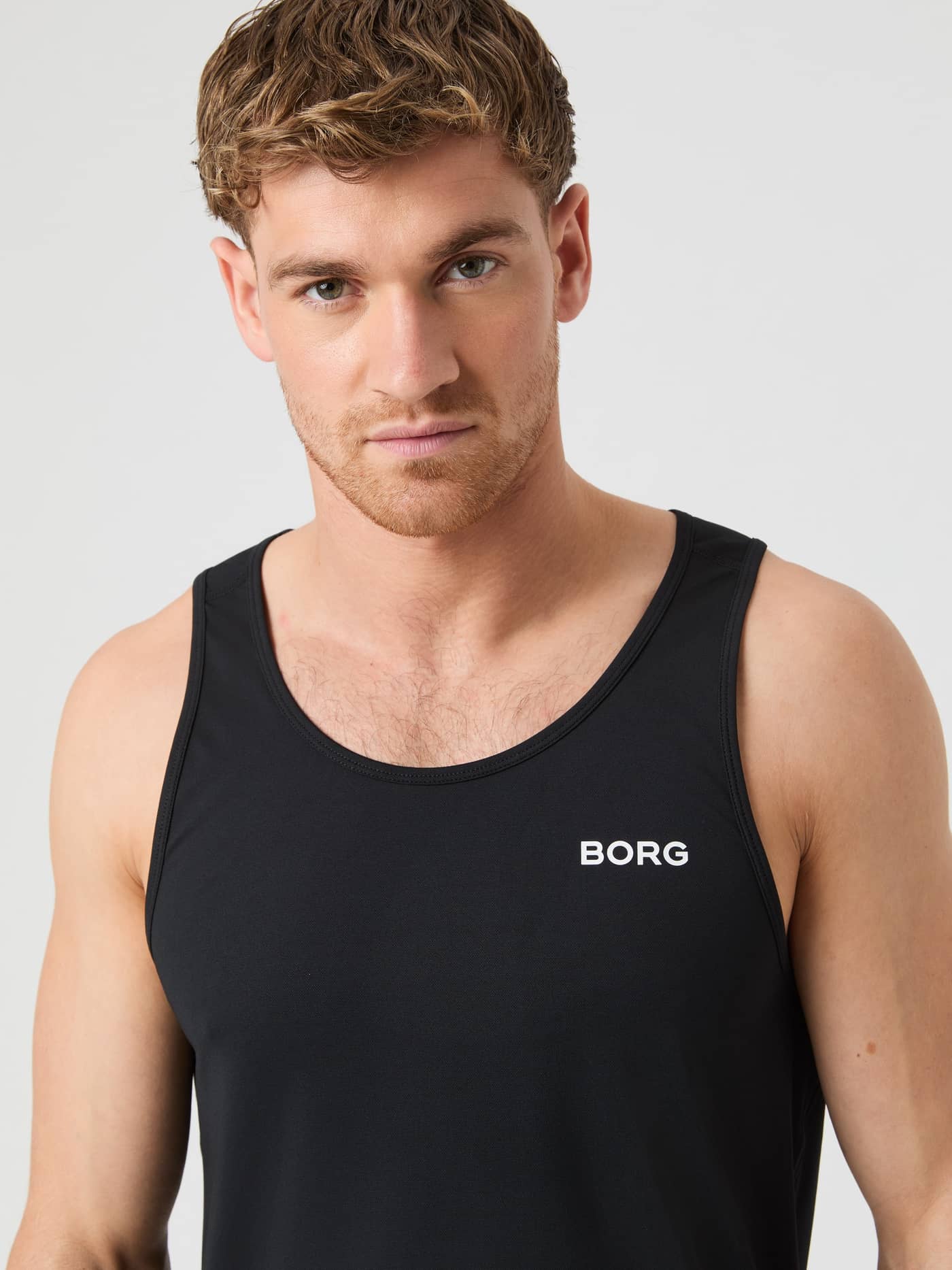 Front close-up of a man in the Borg Athletic Tank in Black Beauty (Black), a moisture-wicking training tank with white logo. - Image 4