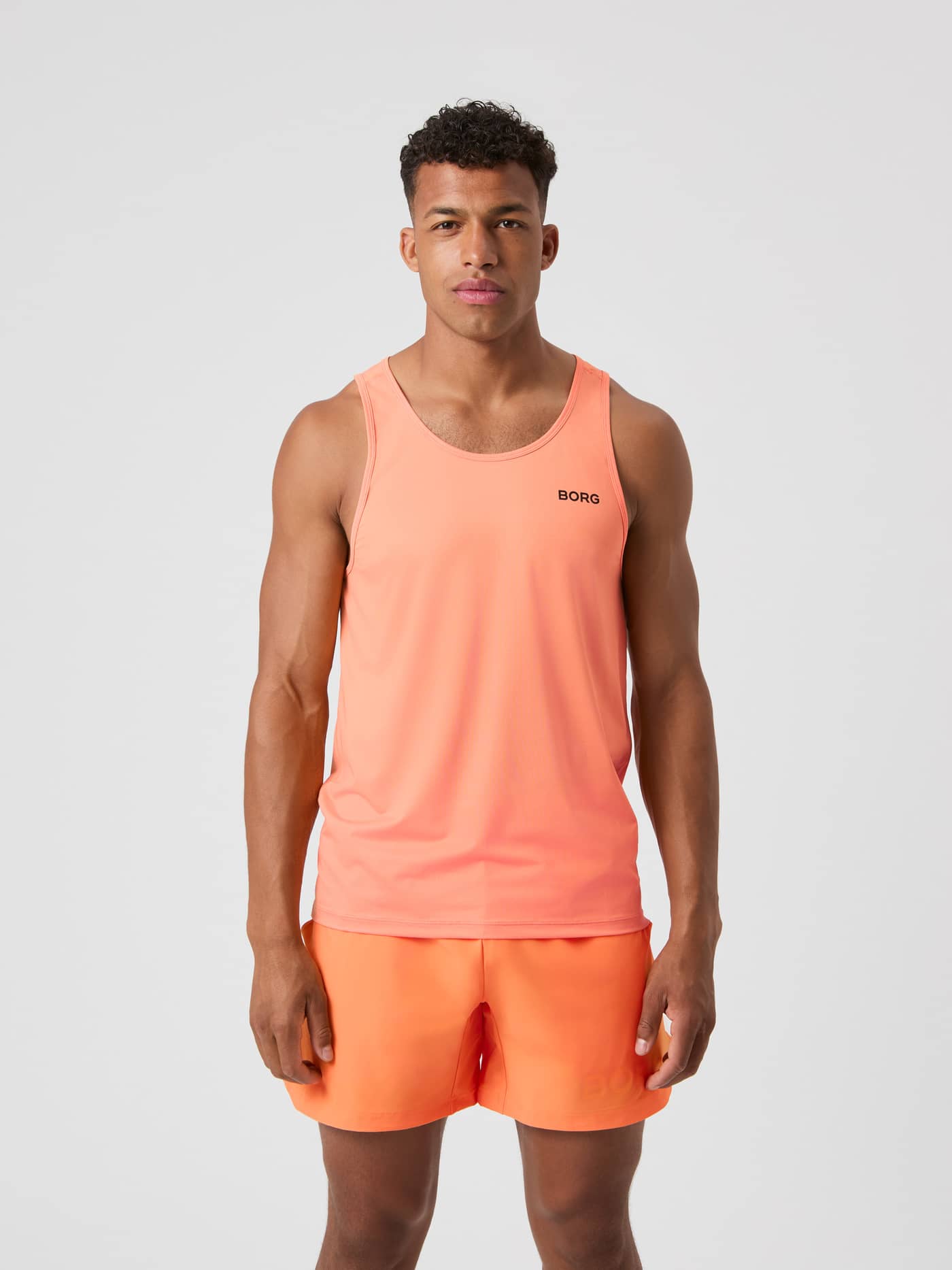 Vooraanzicht van een man in de ademende Björn Borg Athletic Tank in Papaya (Oranje) met zwart logo voor training. - Image 1