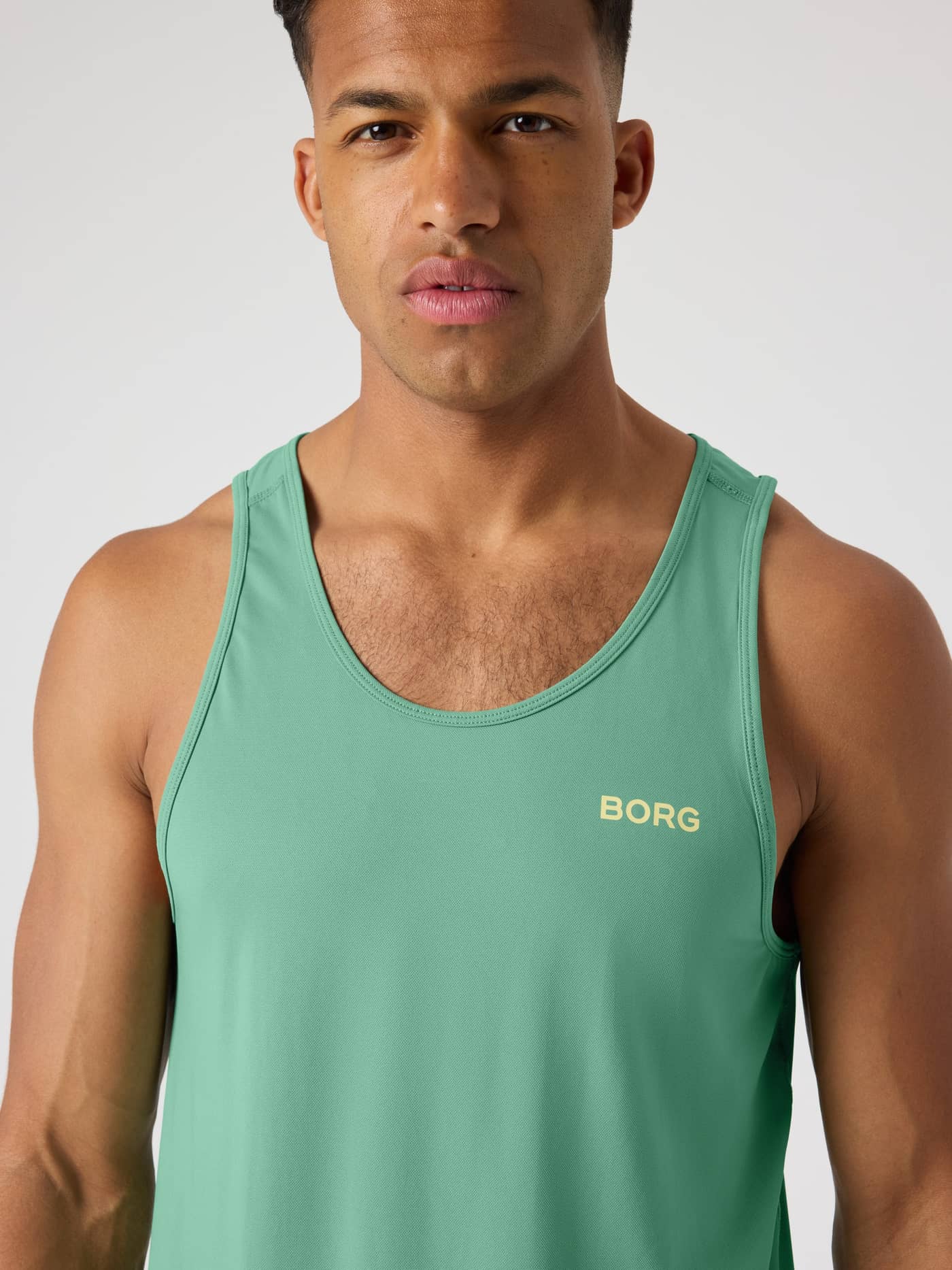 Close-up of the Borg Athletic Tank in Malachite Green (Green), a breathable men's training top with a yellow chest logo. - Image 4