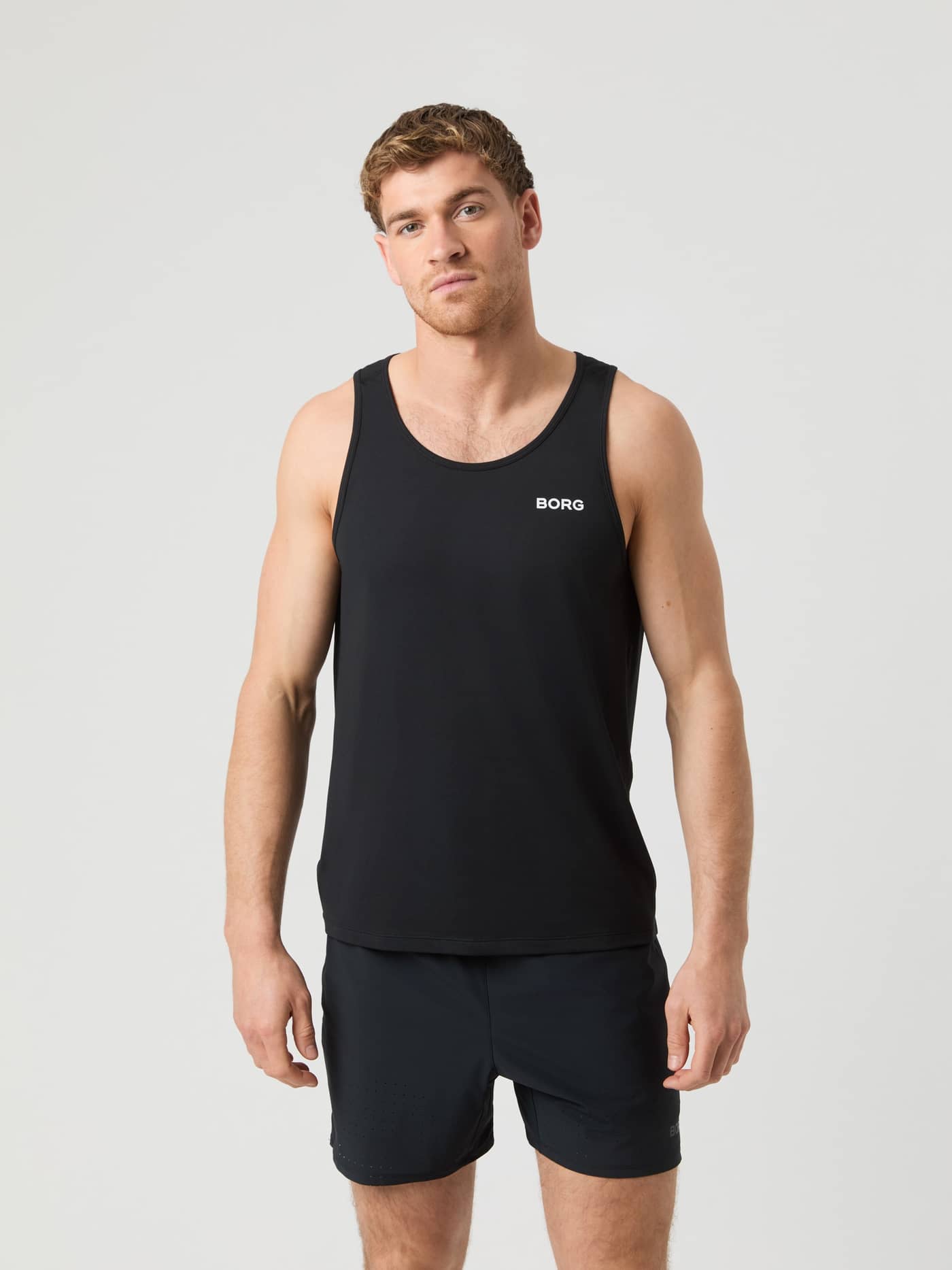 Front view of a man in the Black Beauty (Black) Borg Athletic Tank with a white logo for performance training. - Image 1
