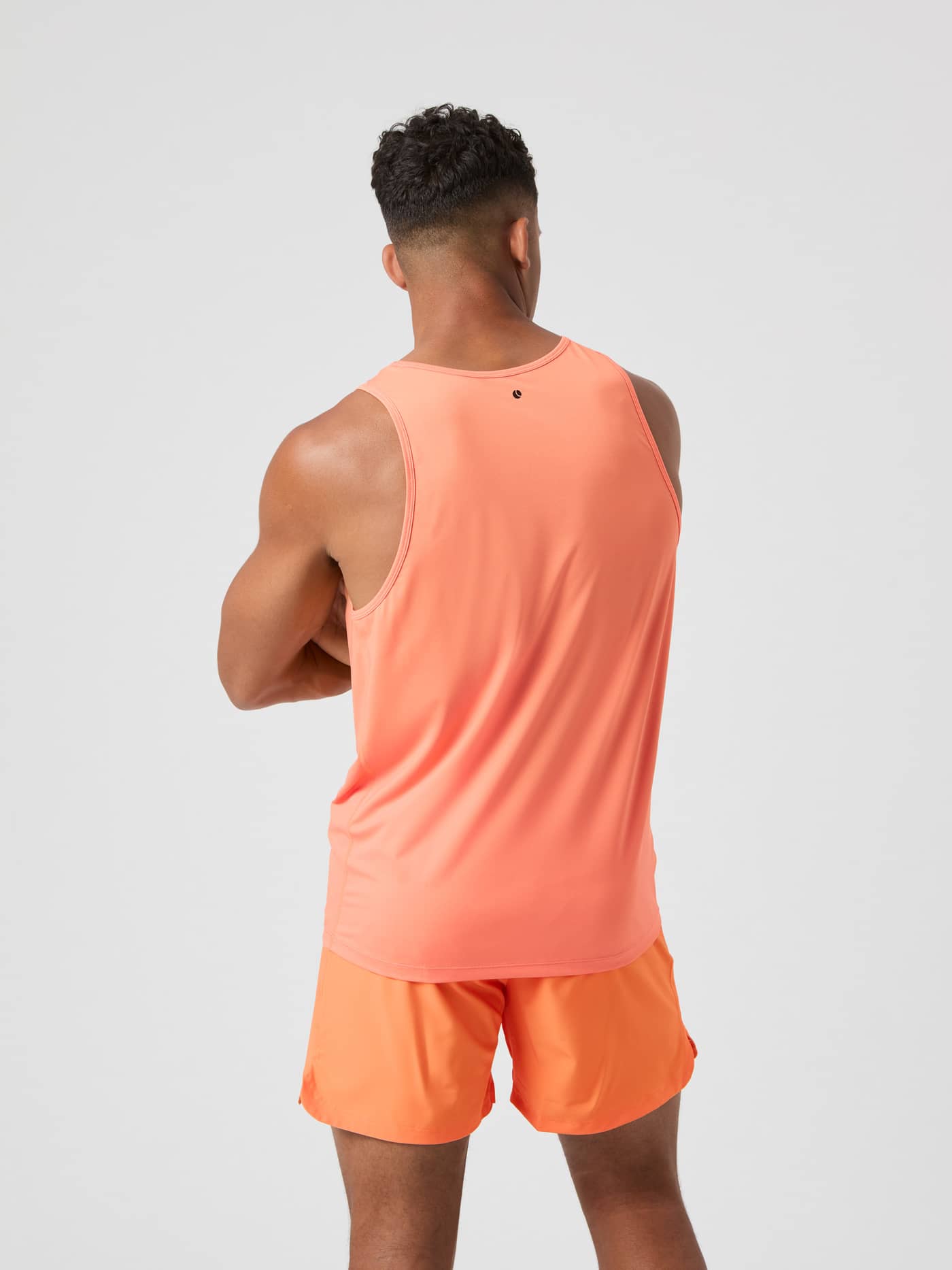Achteraanzicht van een man in de Papaya (Oranje) Borg Athletic Tank met zwart logo, ideaal voor functionele training. - Image 2