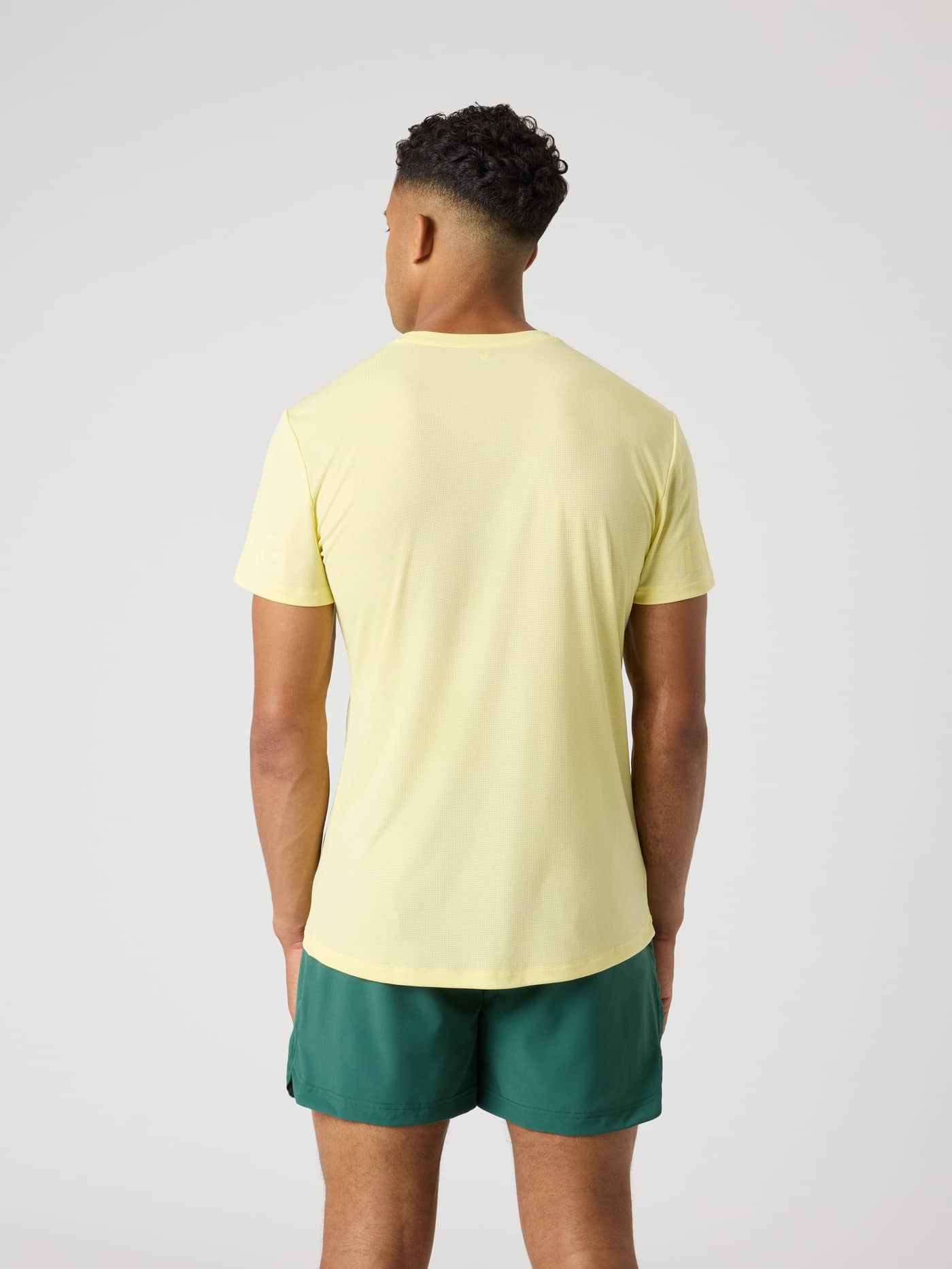 Vista posterior de un hombre con la Borg Light T-Shirt en Lemonade (Amarillo) para tenis y entrenamiento. - Image 2