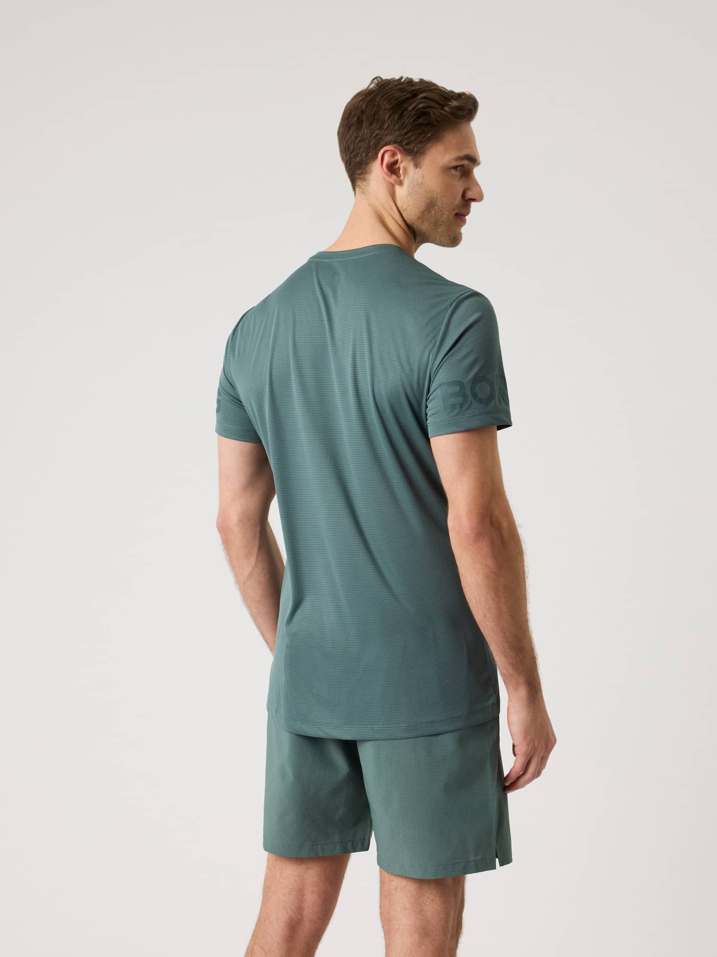 Bakifrån på en man i Borg Light T-Shirt i Balsam Green (Grön), en funktionell träningstopp med gröna logotyper på ärmarna. - Image 2