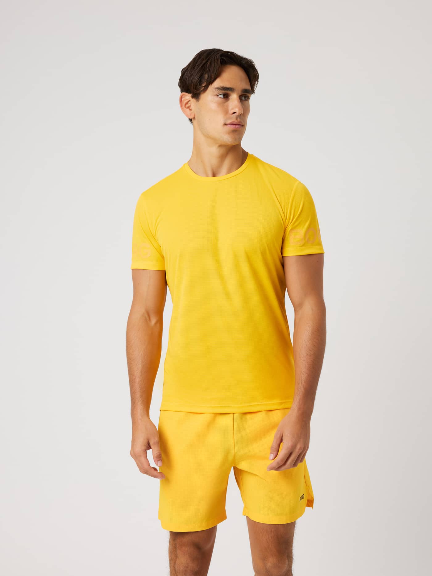 Borg Light T-Shirt i Citrus (Orange) set forfra på en mand, en let trænings-T-shirt med tonale print på ærmerne. - Image 1