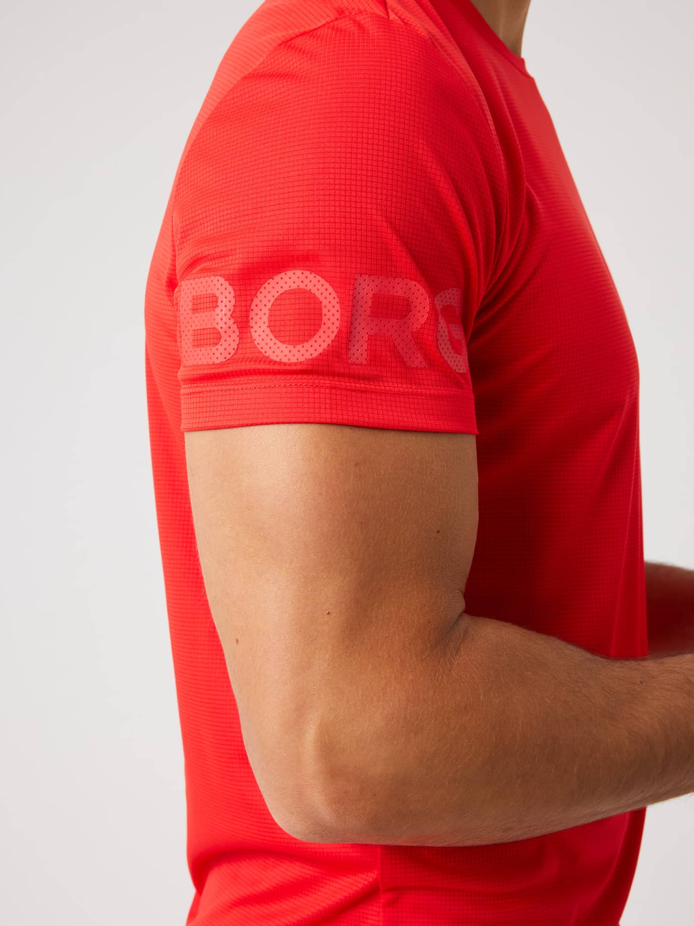 Side view of the Borg Light T-Shirt in Flame Scarlet (Red) with tonal red Borg sleeve print and structured training fabric. - Image 4