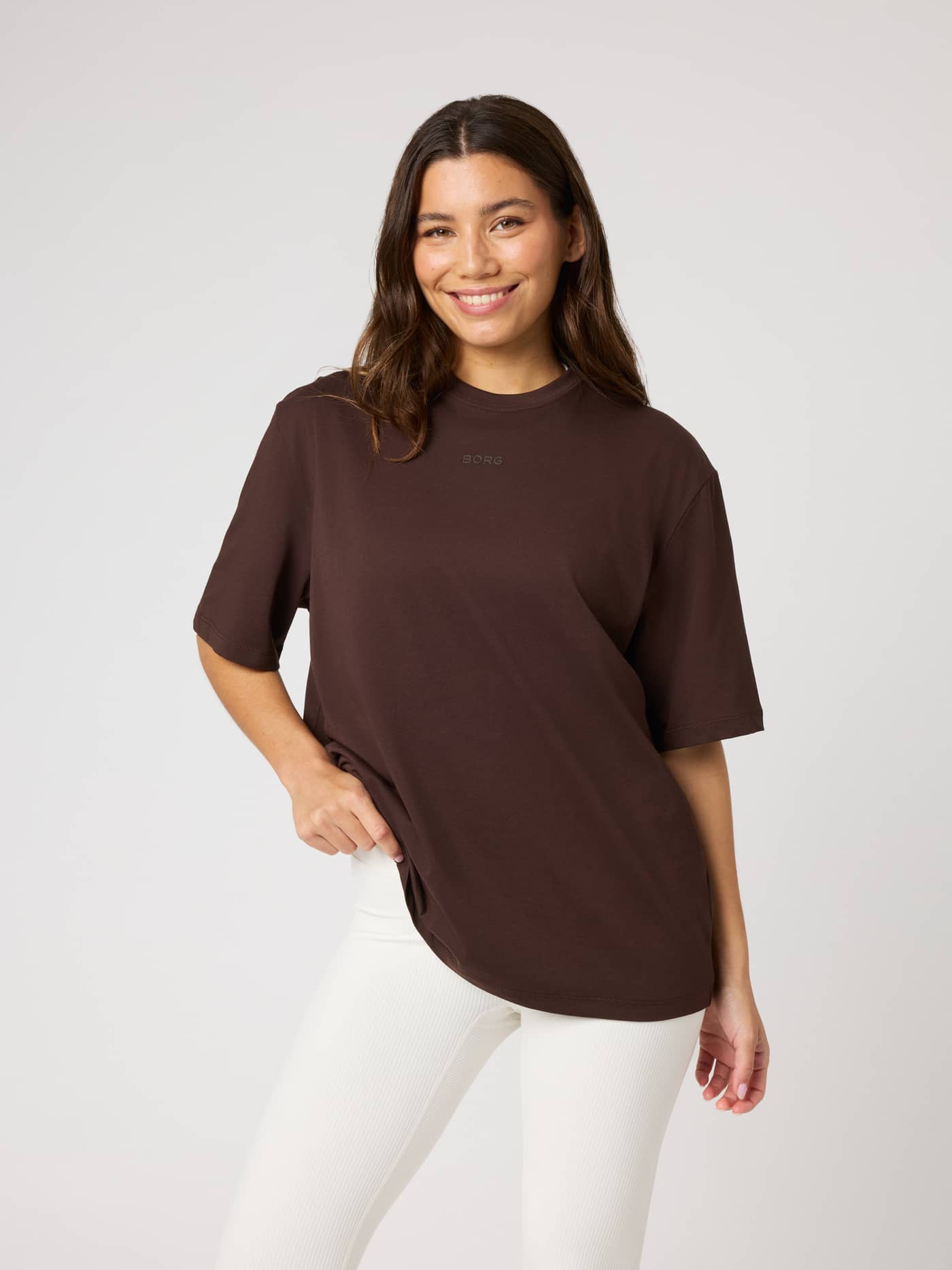 Front view of a model in the Studio Oversized T-Shirt in Coffee Bean (Brown) with a tonal Borg logo for training. - Image 1