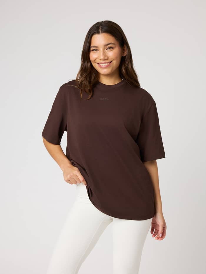 Front view of a model in the Studio Oversized T-Shirt in Coffee Bean (Brown) with a tonal Borg logo for training.