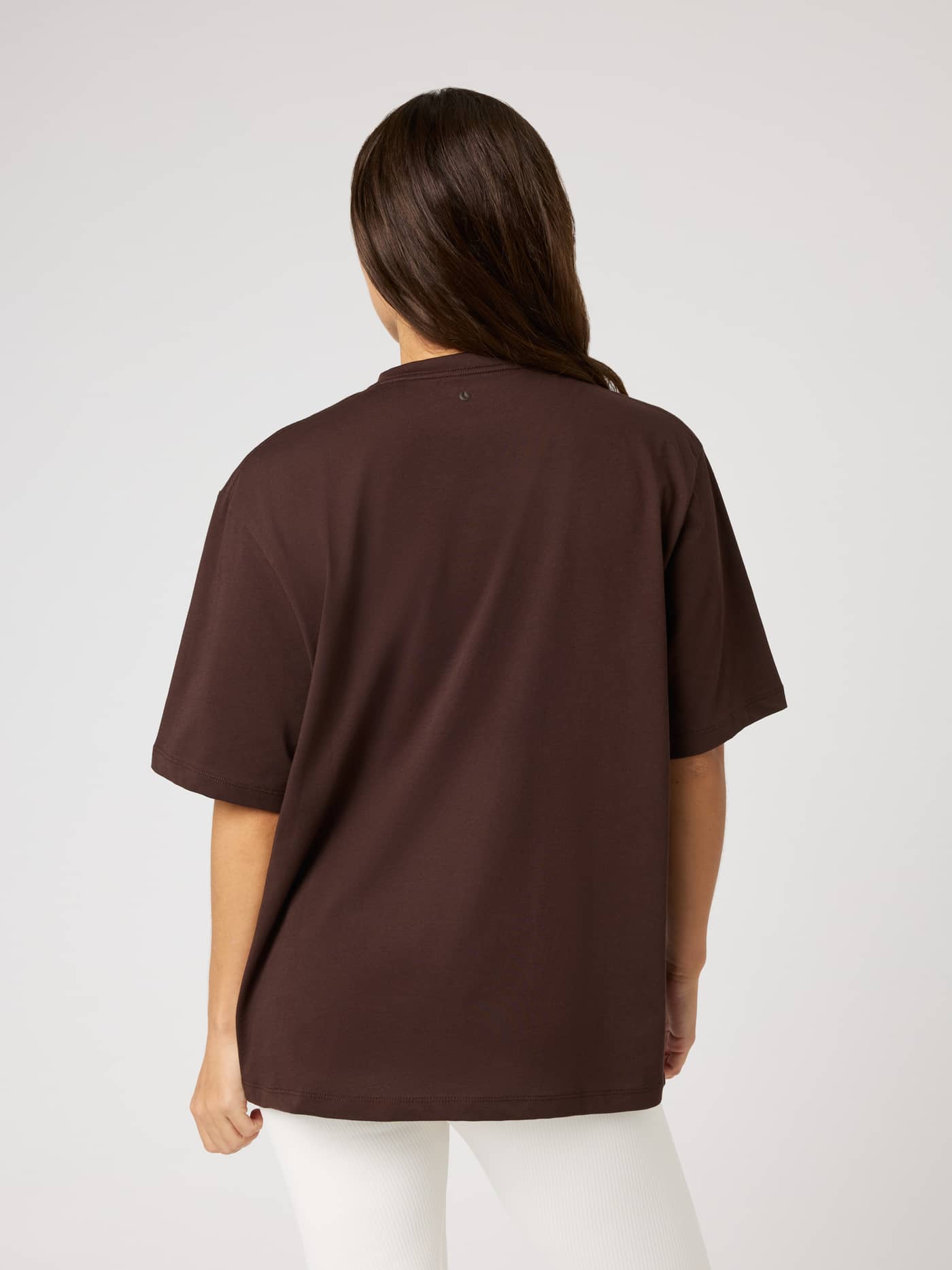 Back view of the Studio Oversized T-Shirt in Coffee Bean (Brown) with a loose fit and black tennis ball logo at the neck. - Image 2