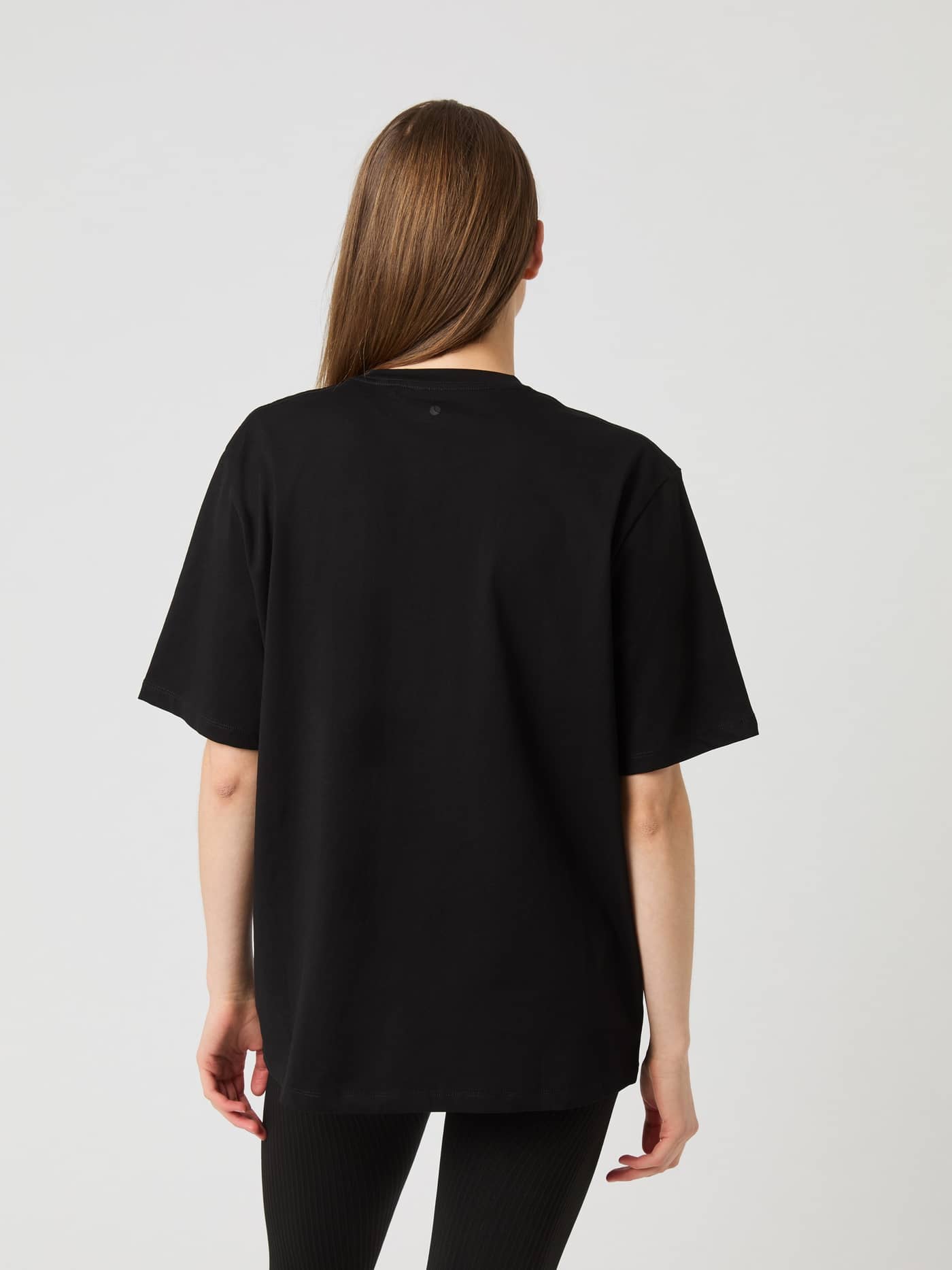 Rückansicht eines Models im Björn Borg Studio Oversized T-Shirt in Black Beauty (Schwarz) mit lockerer Passform für Damen. - Image 2