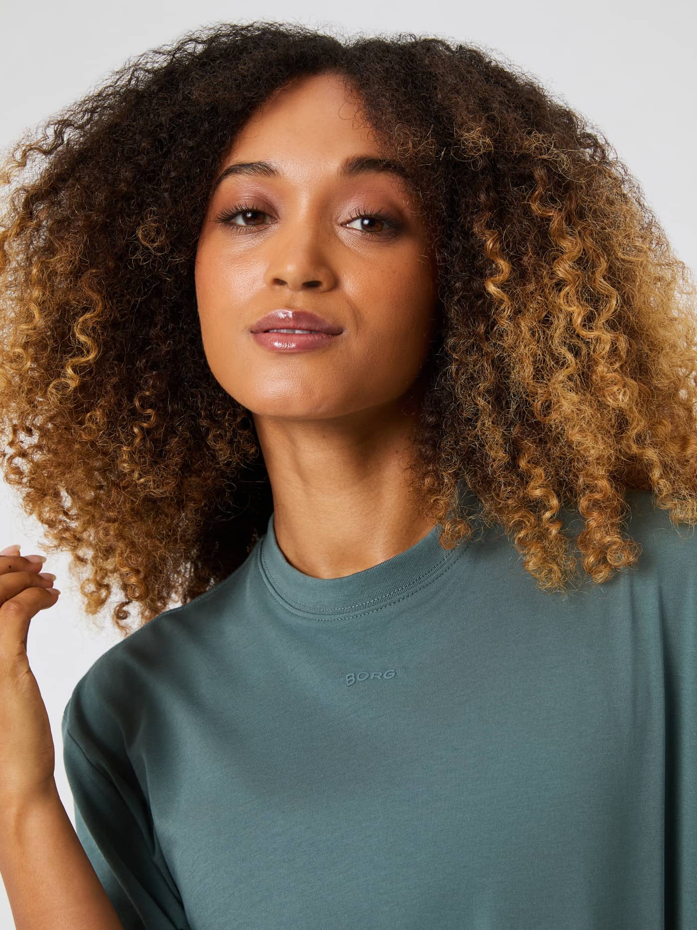 Close-up of a model wearing the Björn Borg Studio Oversized T-Shirt in Balsam Green, focusing on the round neck and logo. - Image 4