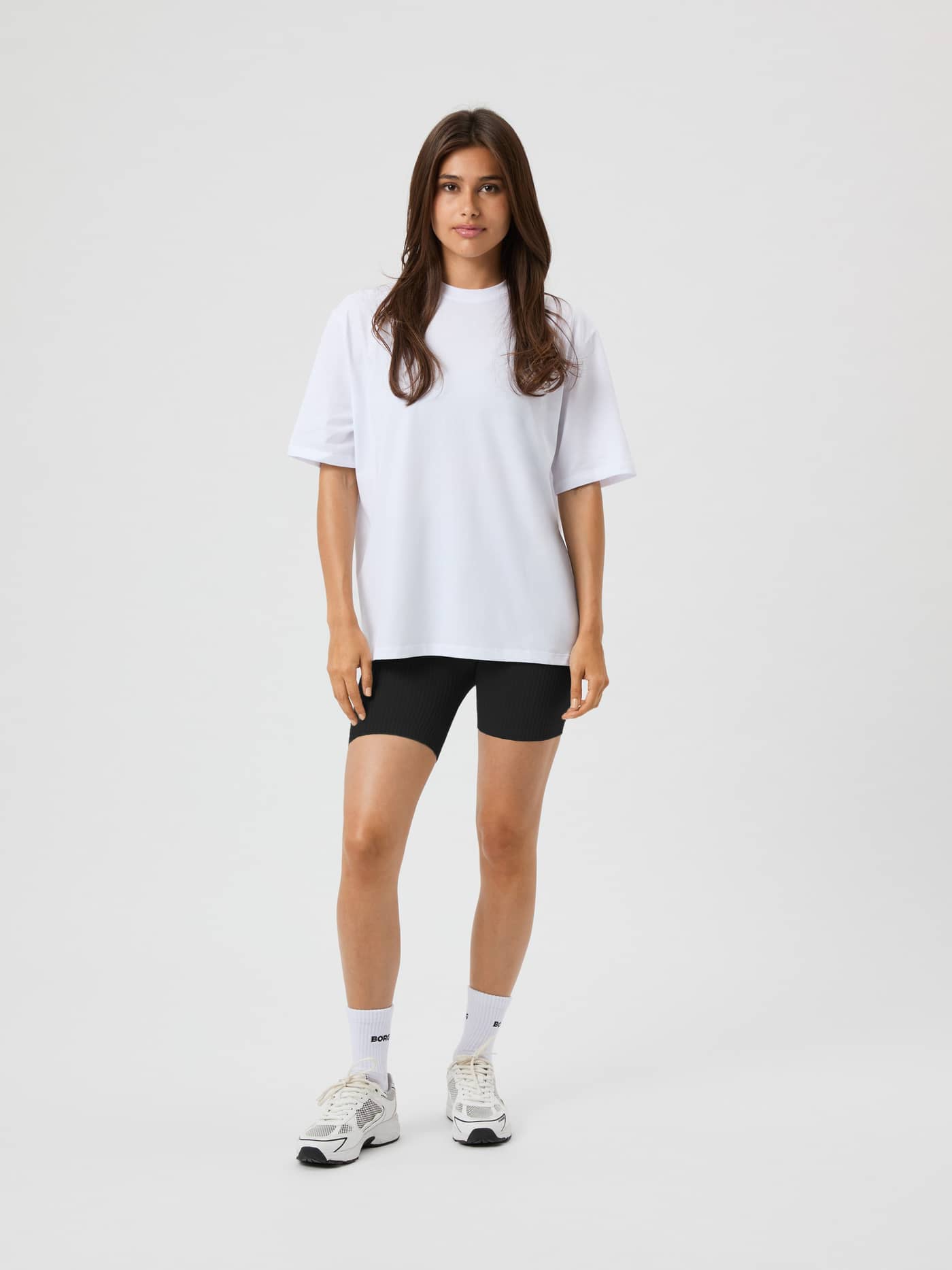 Full-body front view of a woman wearing the Björn Borg Studio Oversized T-Shirt in Brilliant White (White) with a loose fit. - Image 1
