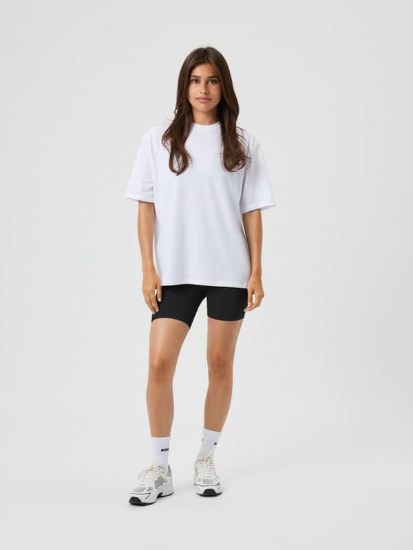 Vue en pied d'une femme portant le Studio Oversized T-Shirt Brilliant White (Blanc) avec une coupe ample et confortable.