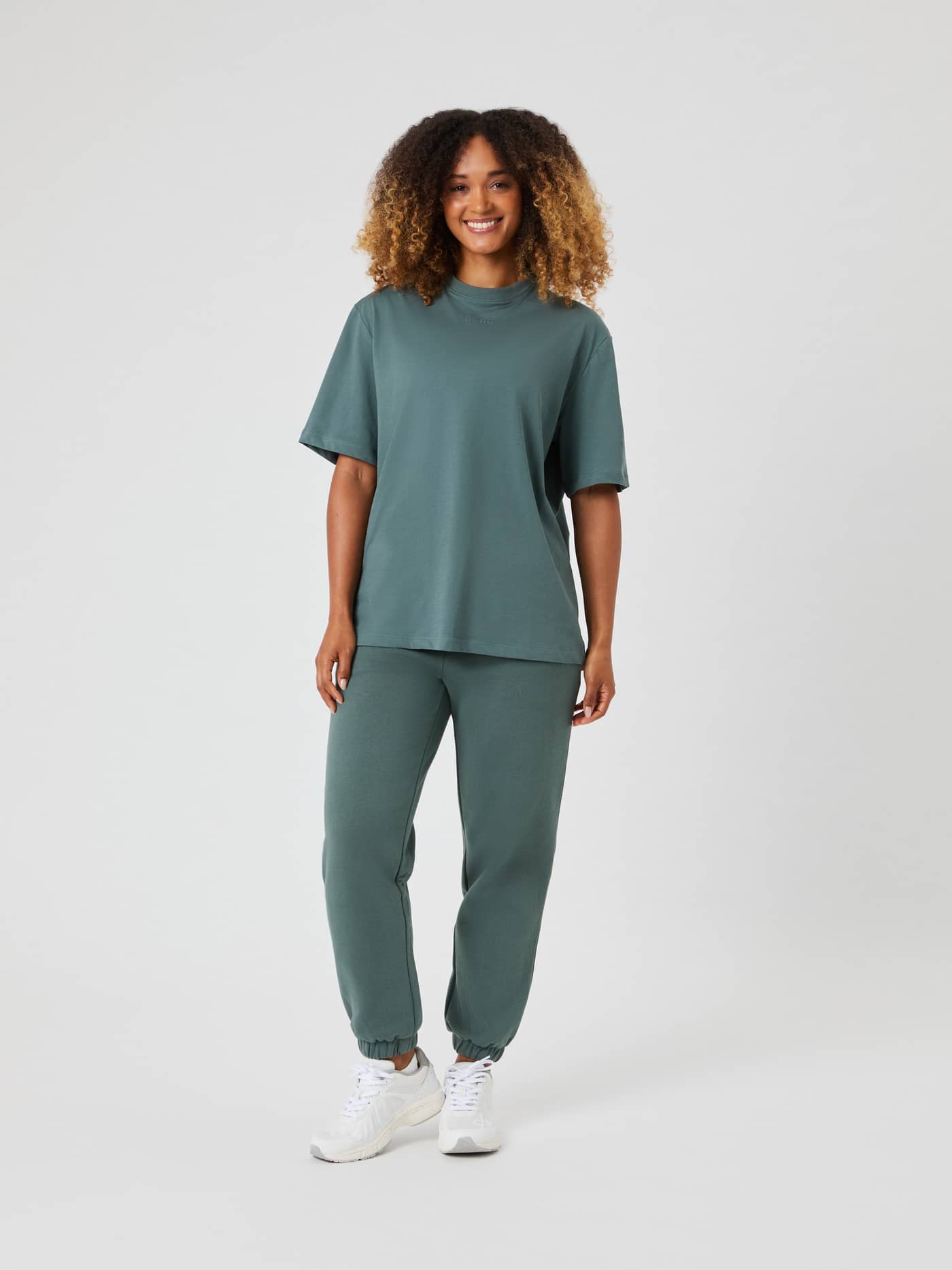 Full-length studio shot of a woman wearing the Björn Borg Studio Oversized T-shirt in Balsam Green with matching sweatpants. - Image 3