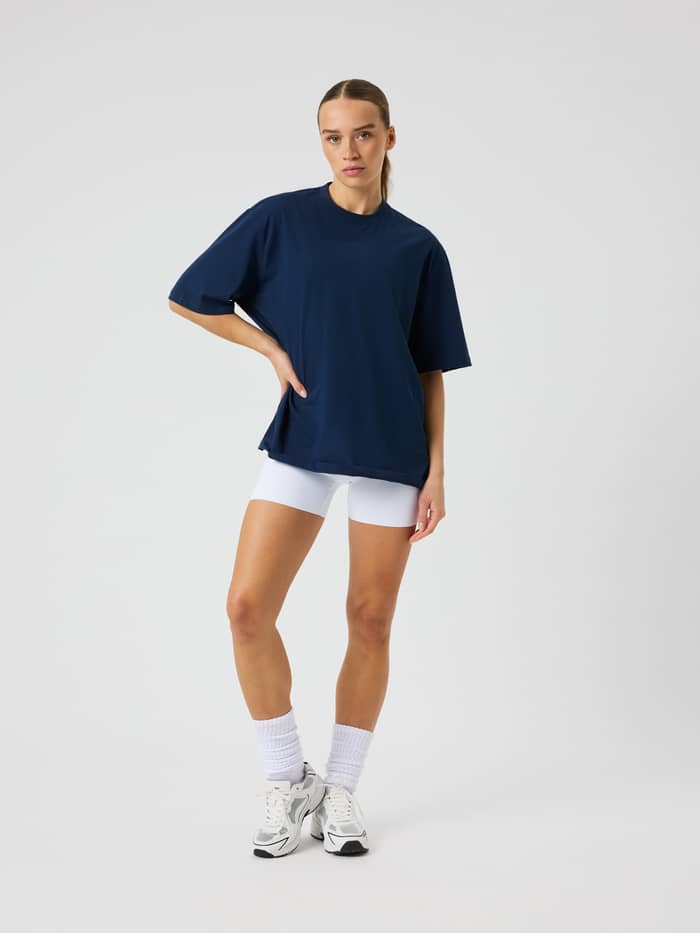 Front view of a female model wearing the Studio Oversized T-Shirt in Dress Blues (Blue) with short sleeves and a loose fit.