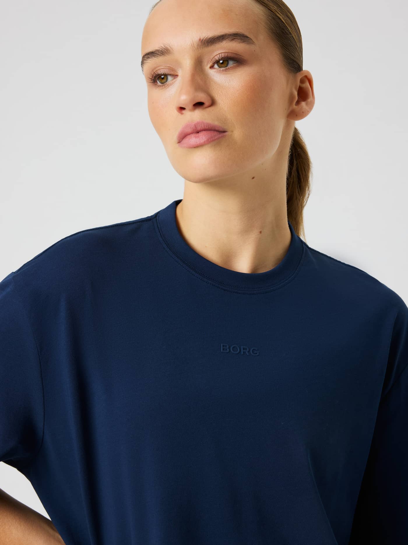 Close-up of the Studio Oversized T-Shirt in Dress Blues (Blue) featuring a round neck and small tone-on-tone logo print. - Image 5