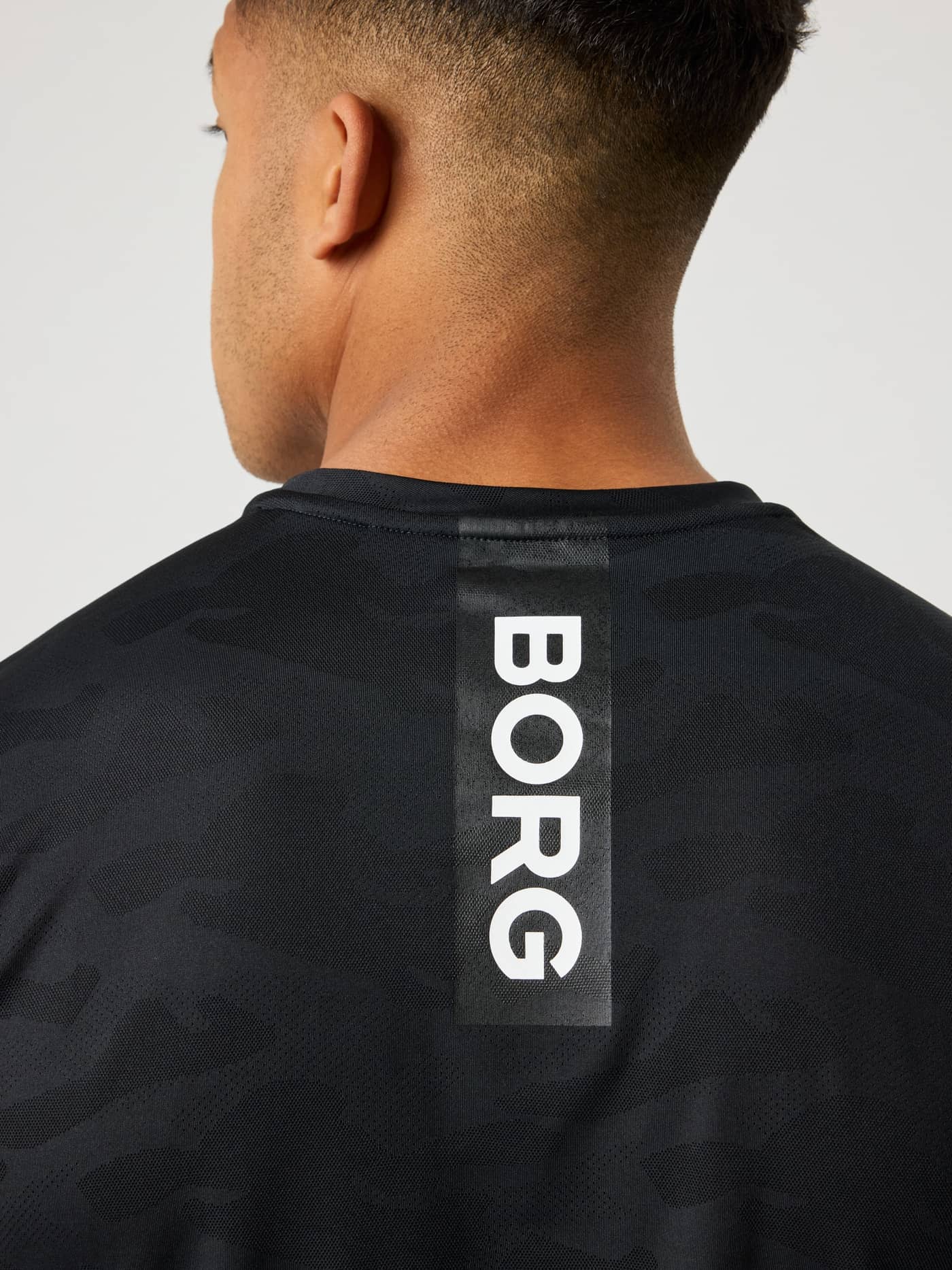 Rückansicht des Borg Performance T-Shirt in Black Beauty (Schwarz) für Training mit Camo-Muster und weißem, vertikalem Logo. - Image 4