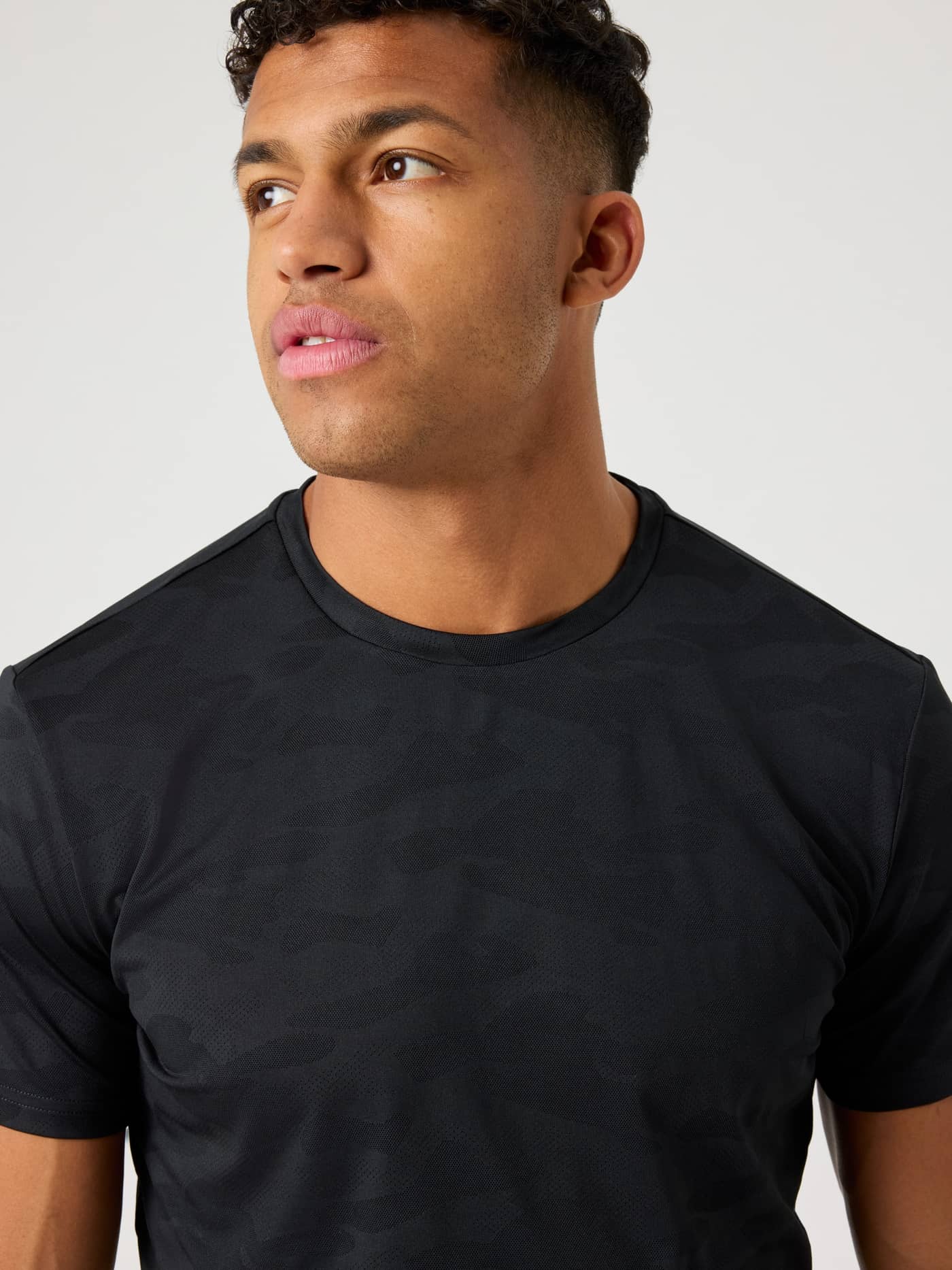 Nahaufnahme eines Mannes im Borg Performance T-Shirt in Black Beauty (Schwarz) mit Jacquard-Camouflage-Muster zum Training. - Image 5