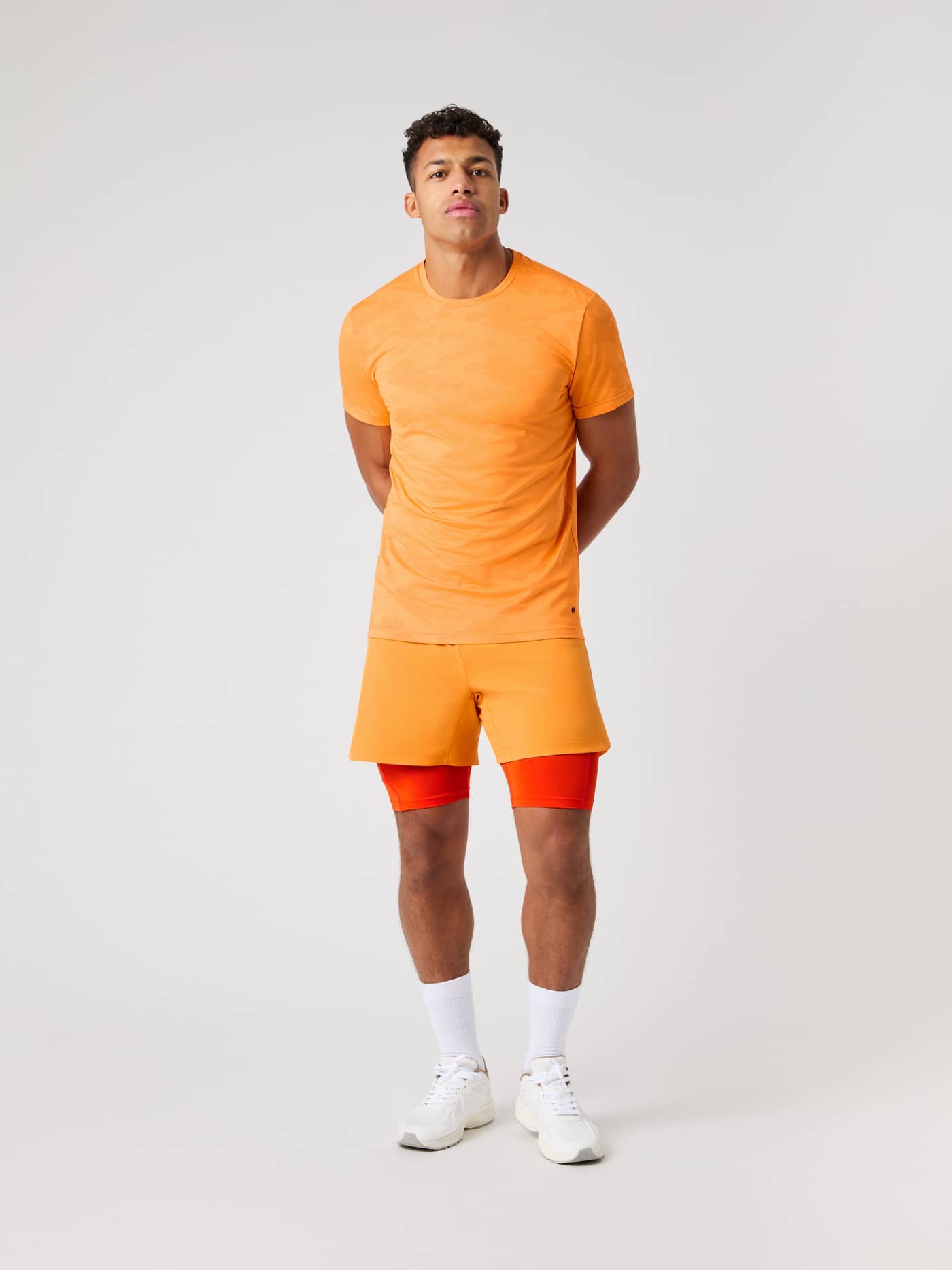 Vorderansicht eines Mannes im Borg Performance T-Shirt in Sun Orange (Orange) mit Camo-Muster für das Training. - Image 4