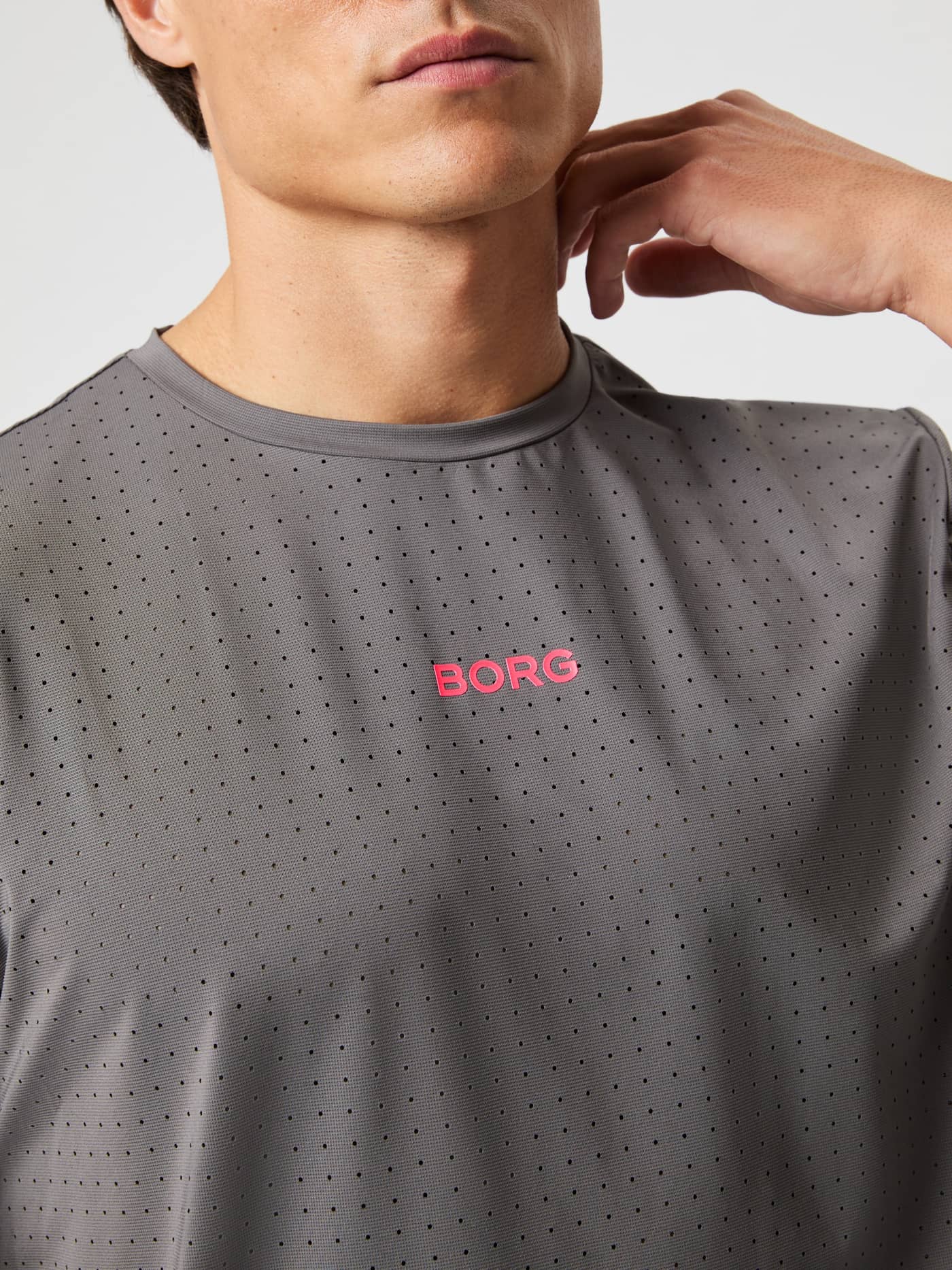 Nahaufnahme des funktionalen Borg Performance Perforated T-Shirt in Granite Gray (Grau) mit pinkem Logo zum Laufen. - Image 6