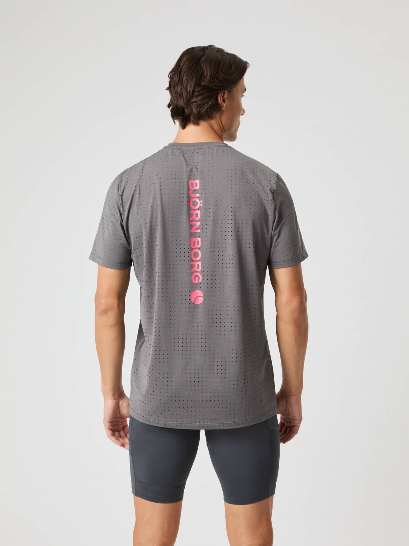 Rückansicht eines Mannes im Borg Performance Perforated T-Shirt in Granite Gray (Grau) mit pinkem Logo zum Laufen. - Image 2